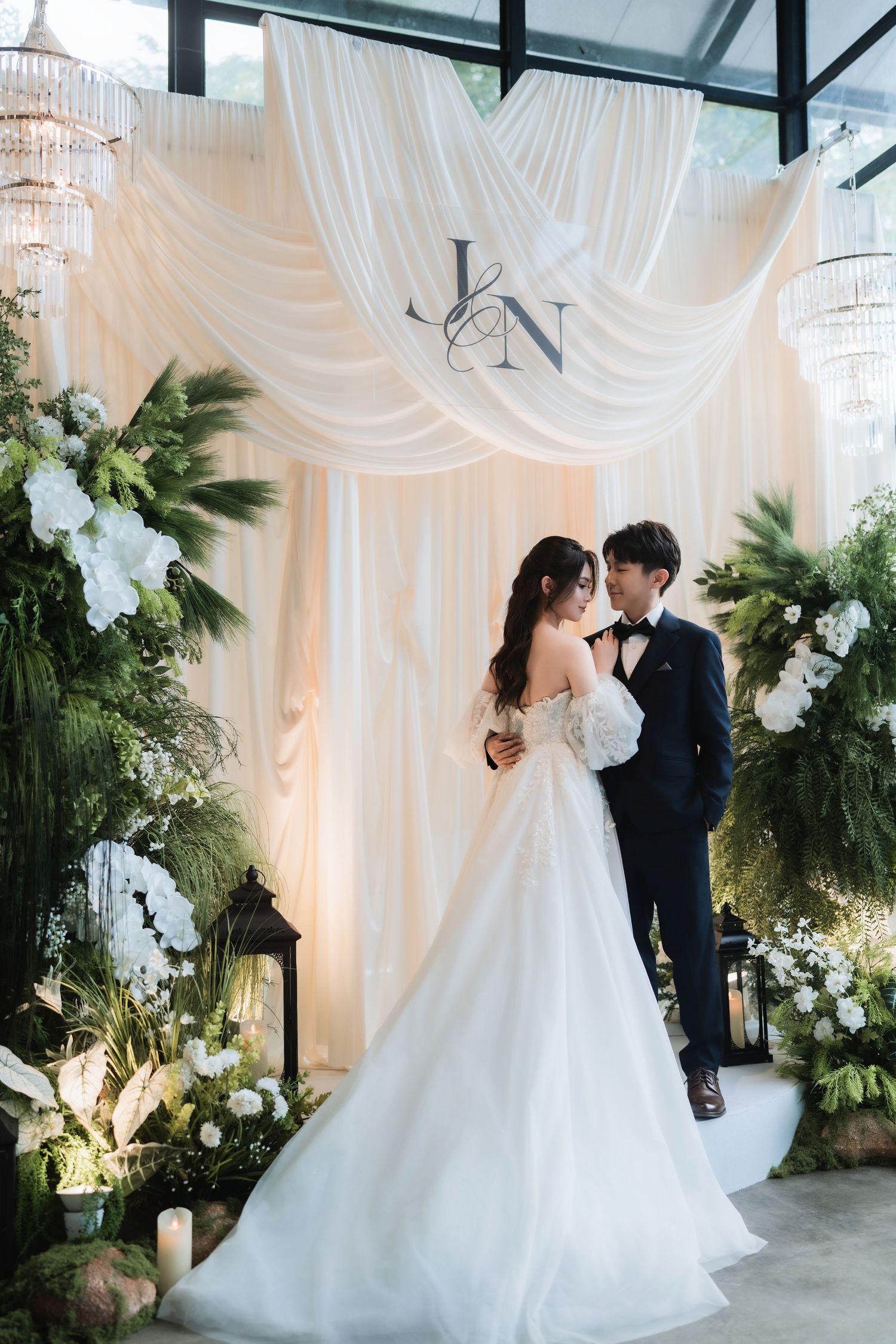A romantic wedding scene with white drapes, chandeliers, and floral decorations creating an elegant indoor backdrop at Inside Out Cafe.