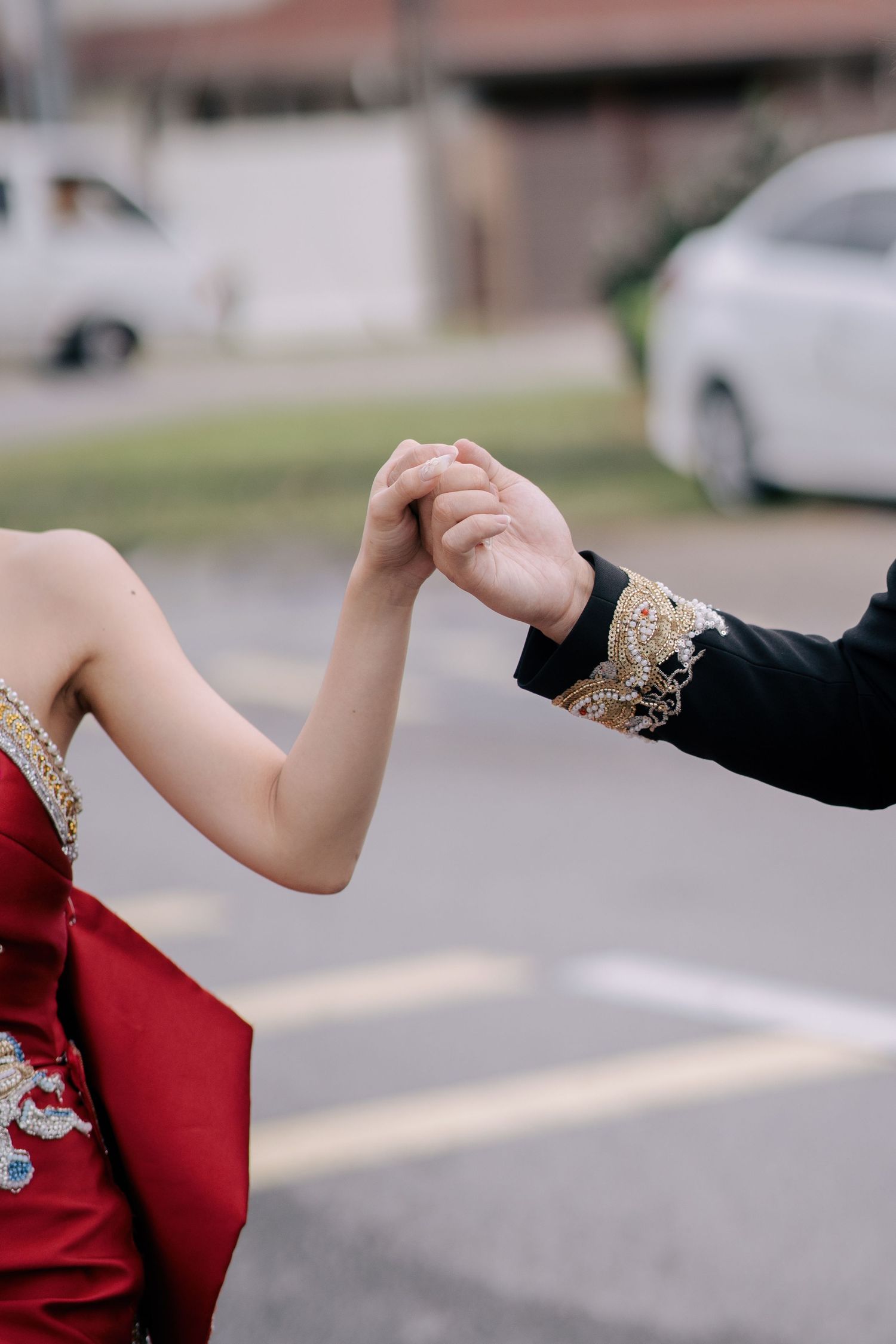Close-up of a couple holding hands, highlighting the craftsmanship of Traditional Chinese Wedding Penang attire