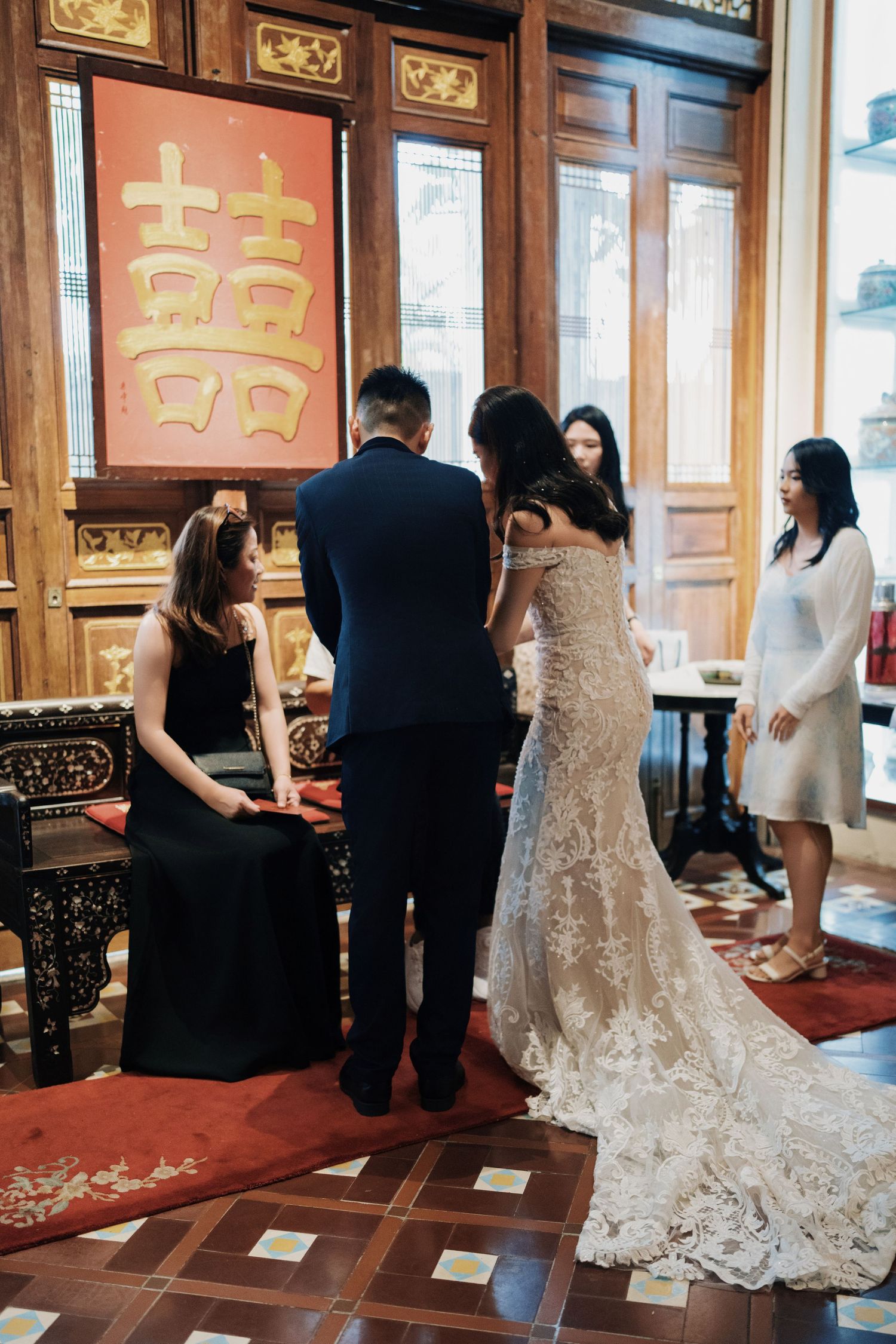 Bride and groom kneeling for elders in front of a Double Happiness sign at Seven Terraces