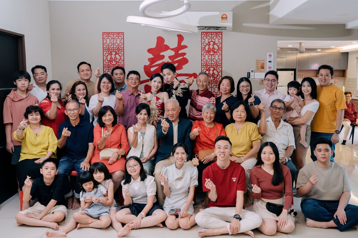 Extended family members celebrate a Traditional Chinese Wedding in Penang with a group photo and finger-heart poses
