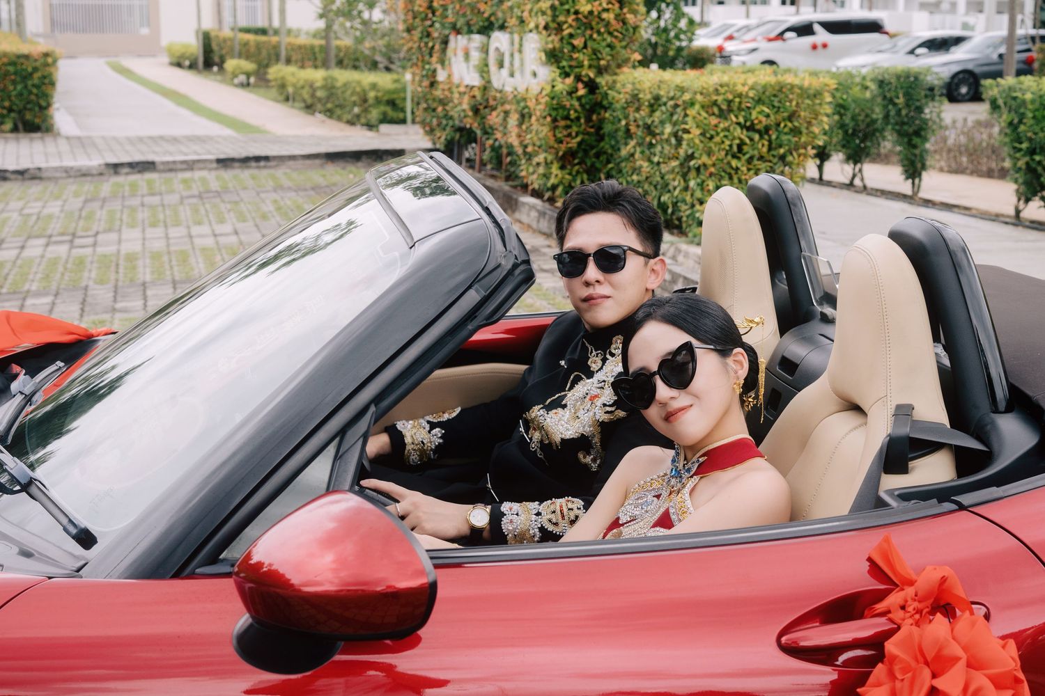 Modern Chinese bridal couple in a red Mazda MX-5 wedding car wearing heart sunglasses