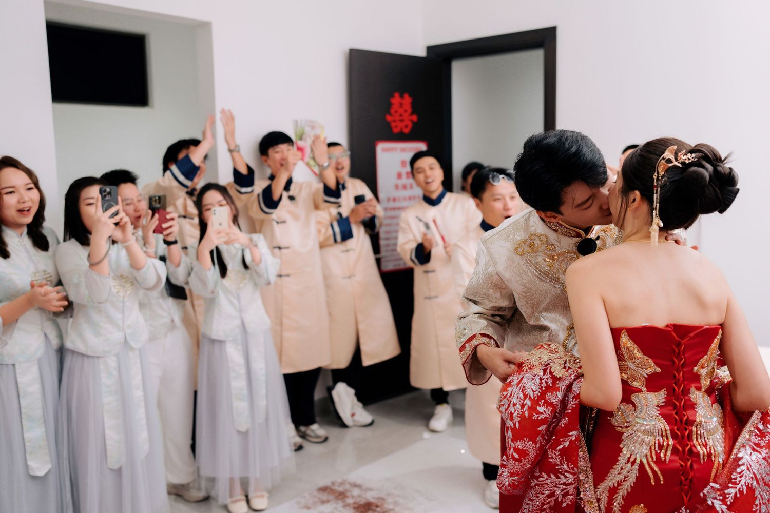 Wedding party members celebrate in a room decorated with traditional Chinese symbols.
