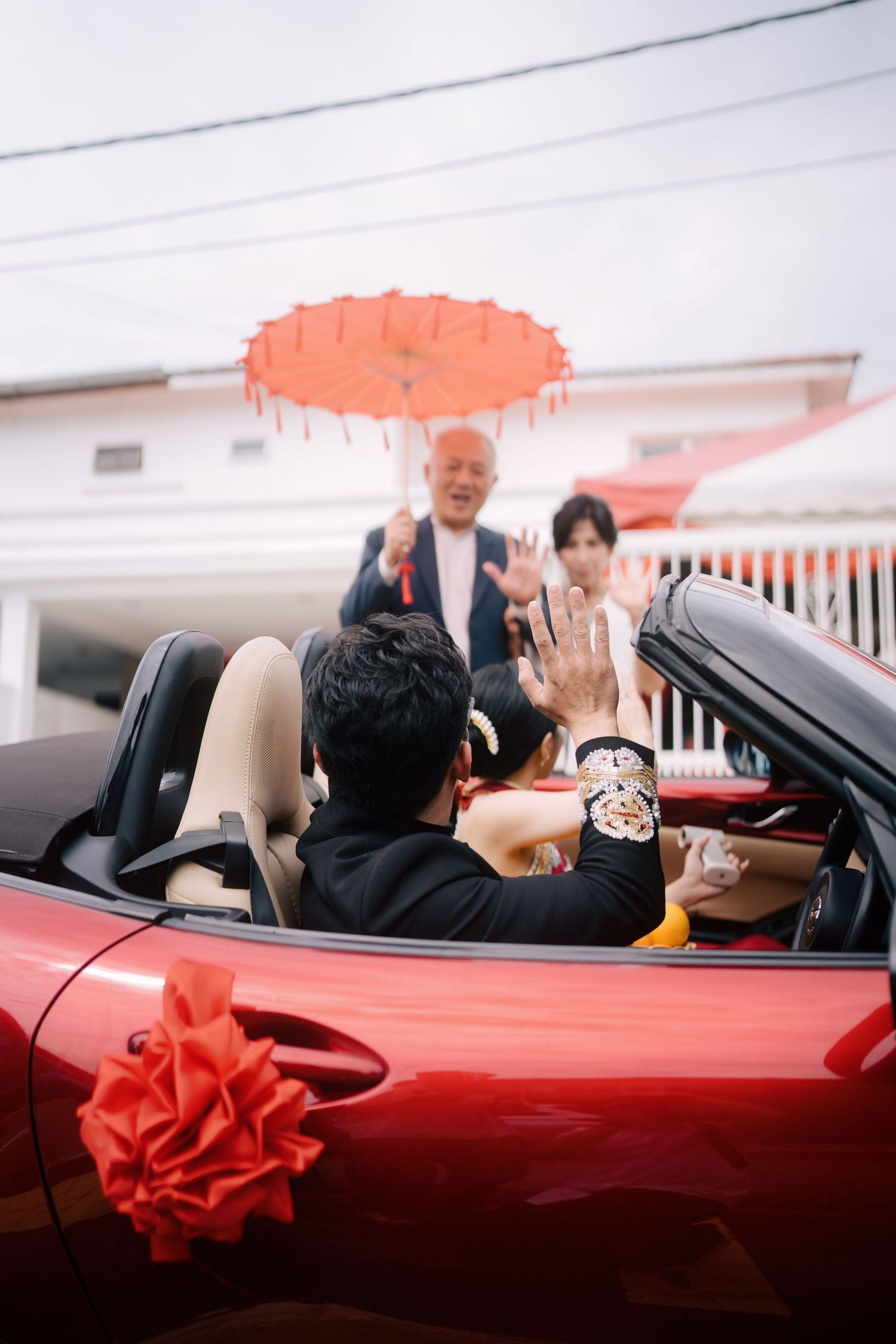 Parents bidding farewell to the bride and groom as they depart in their wedding car