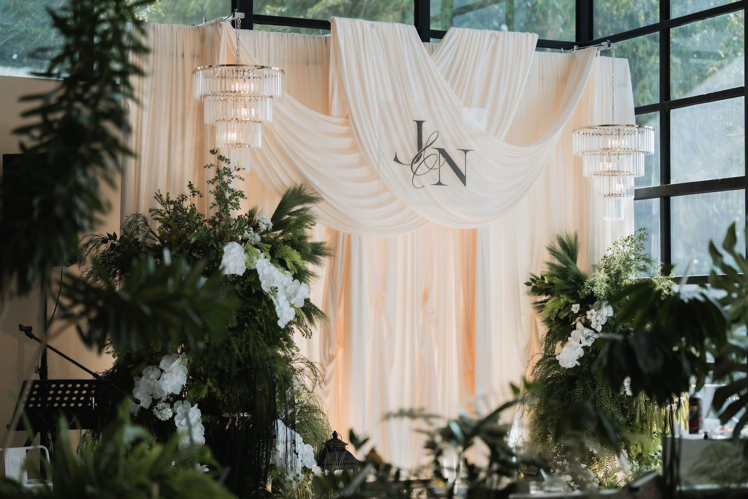 Modern wedding venue with floor-to-ceiling windows and elegant white drapery decorations.