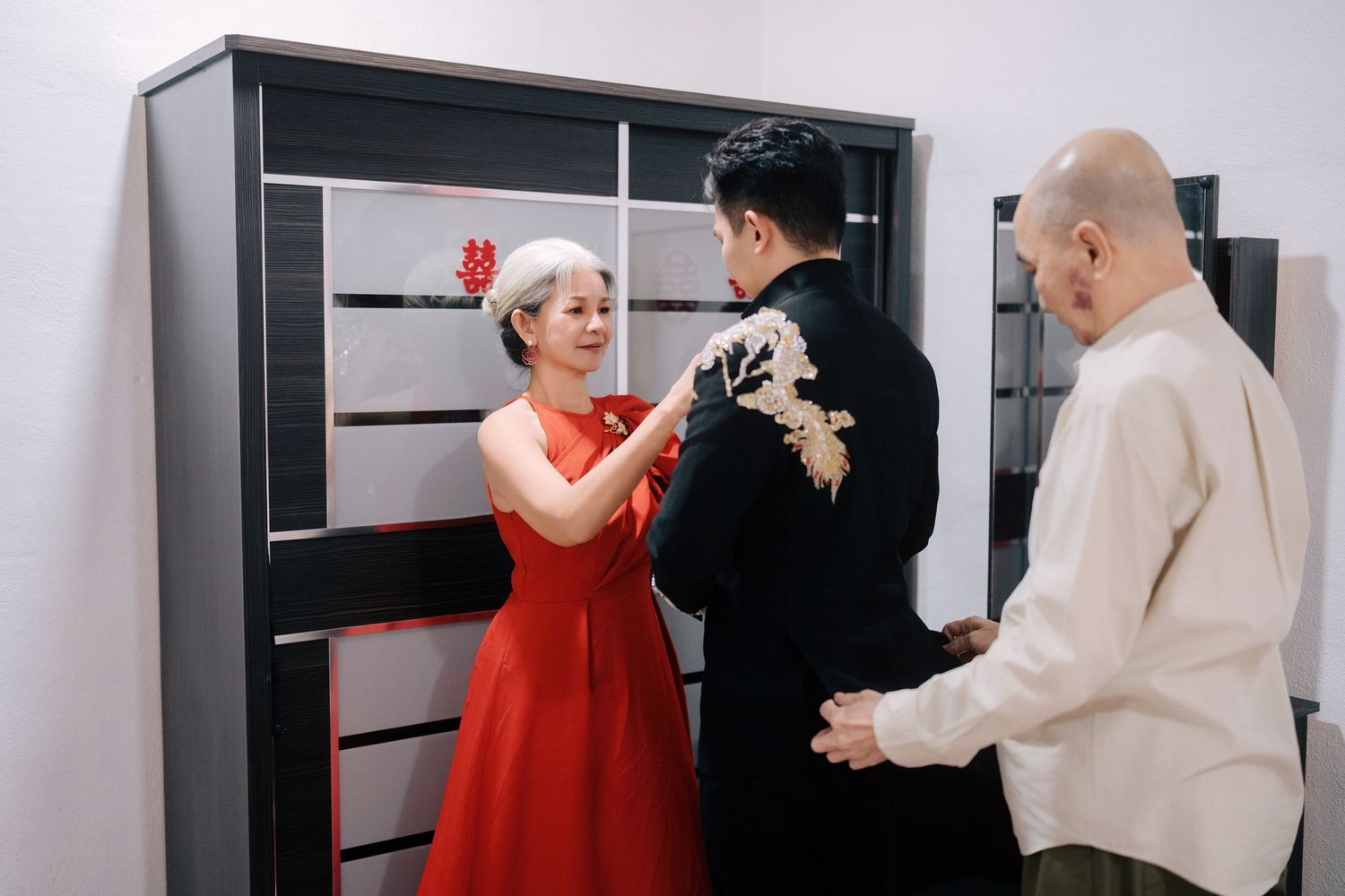 Parents assisting the groom with his wedding attire, a touching moment of Chinese wedding tradition