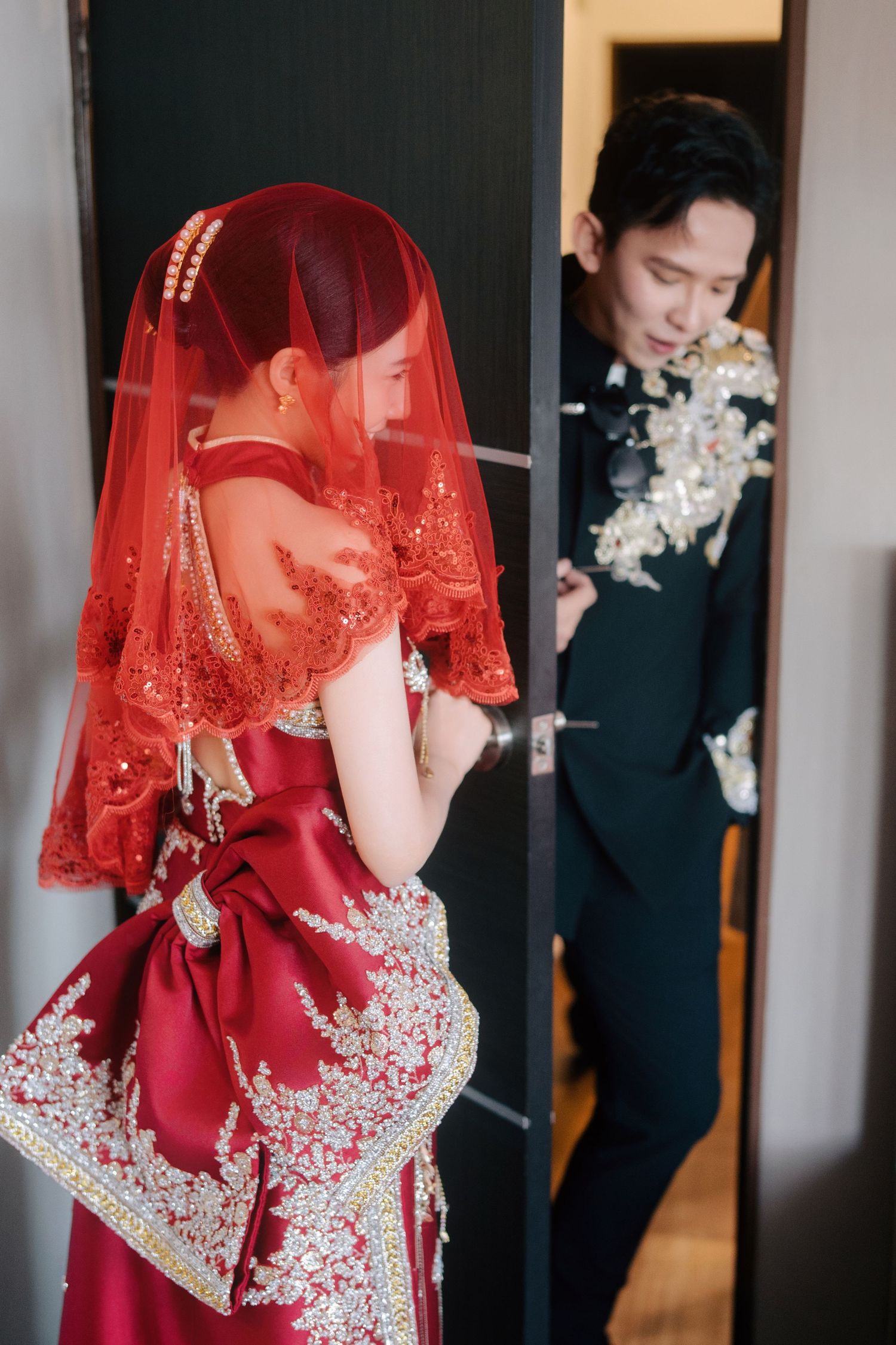 Bride in a modern qupao with a large back bow meeting the groom at a traditional Chinese wedding