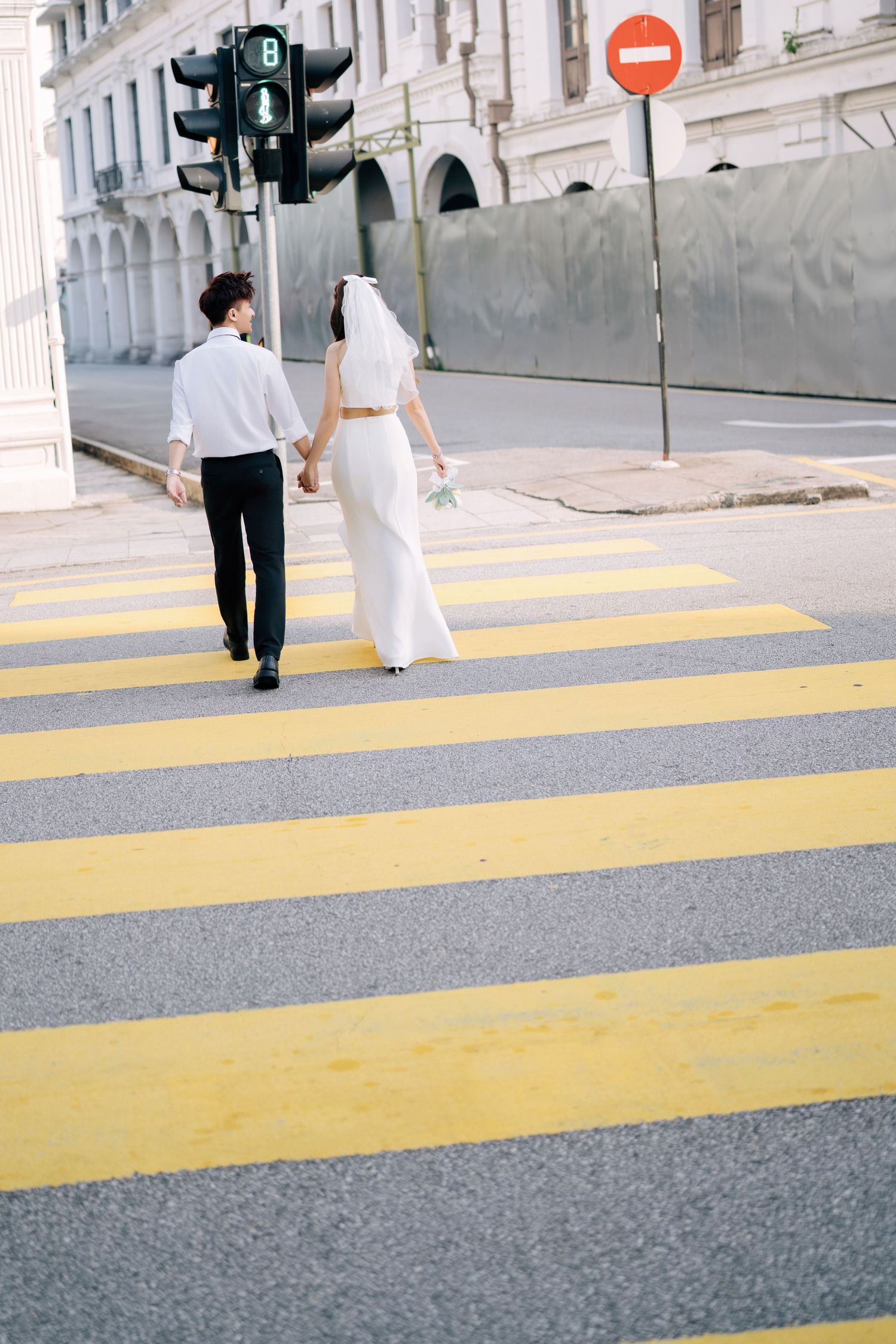 Couple walks across yellow pedestrian crossing in urban setting.