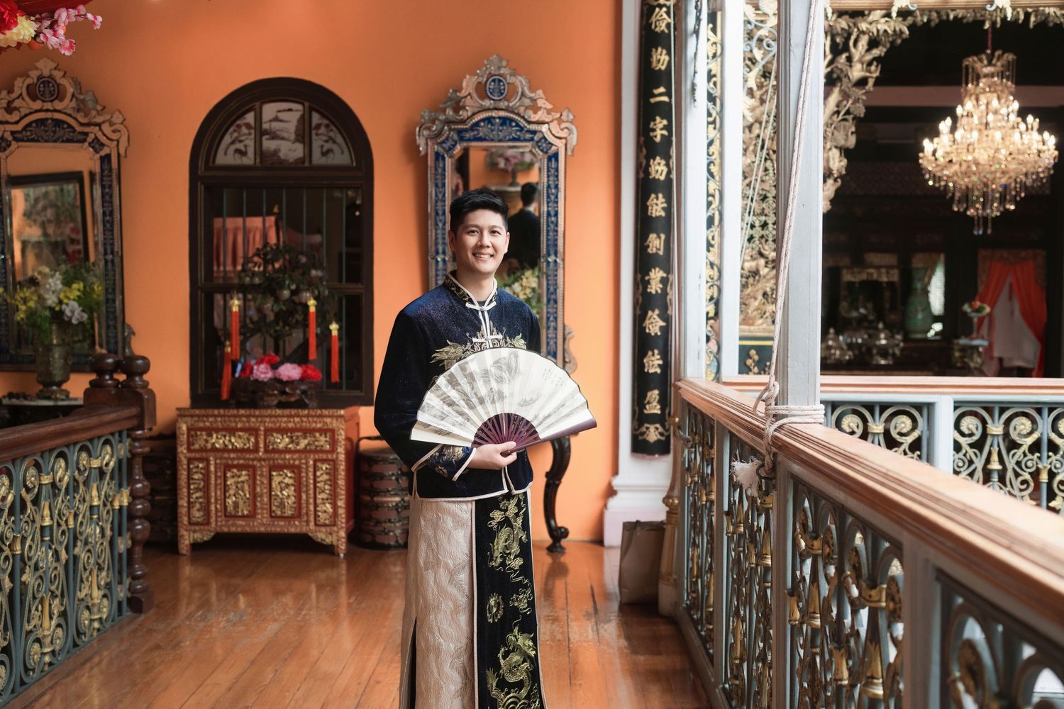 Traditional Chinese groom's attire featuring an embroidered navy Changshan and folding fan