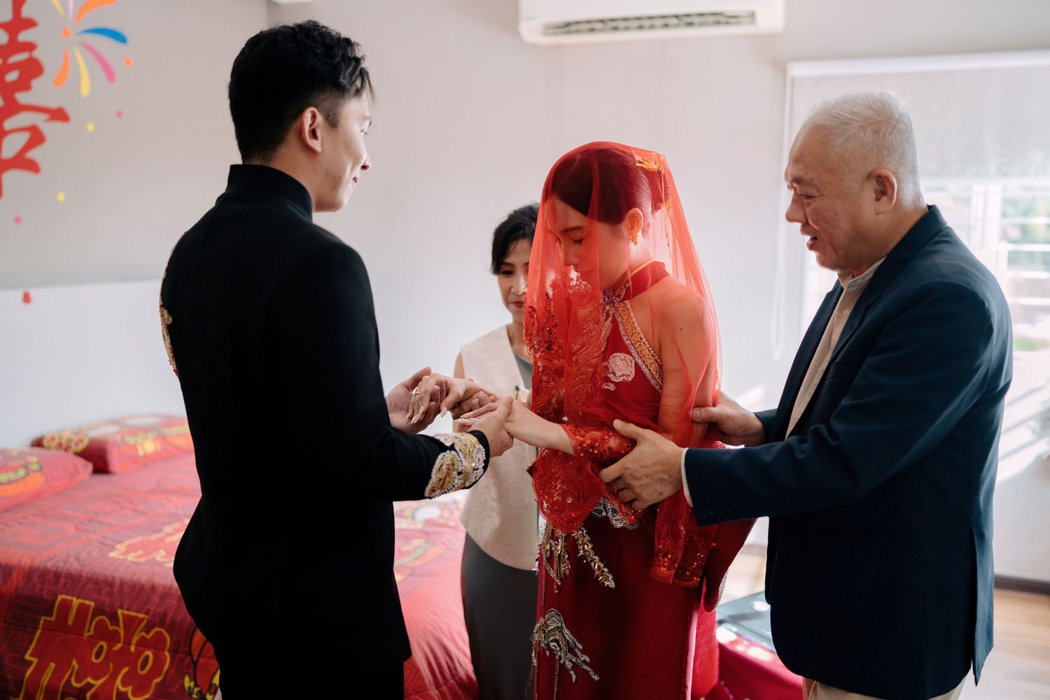 Chinese wedding traditions showing the bride’s parents witnessing the couple joining hands in the bedroom