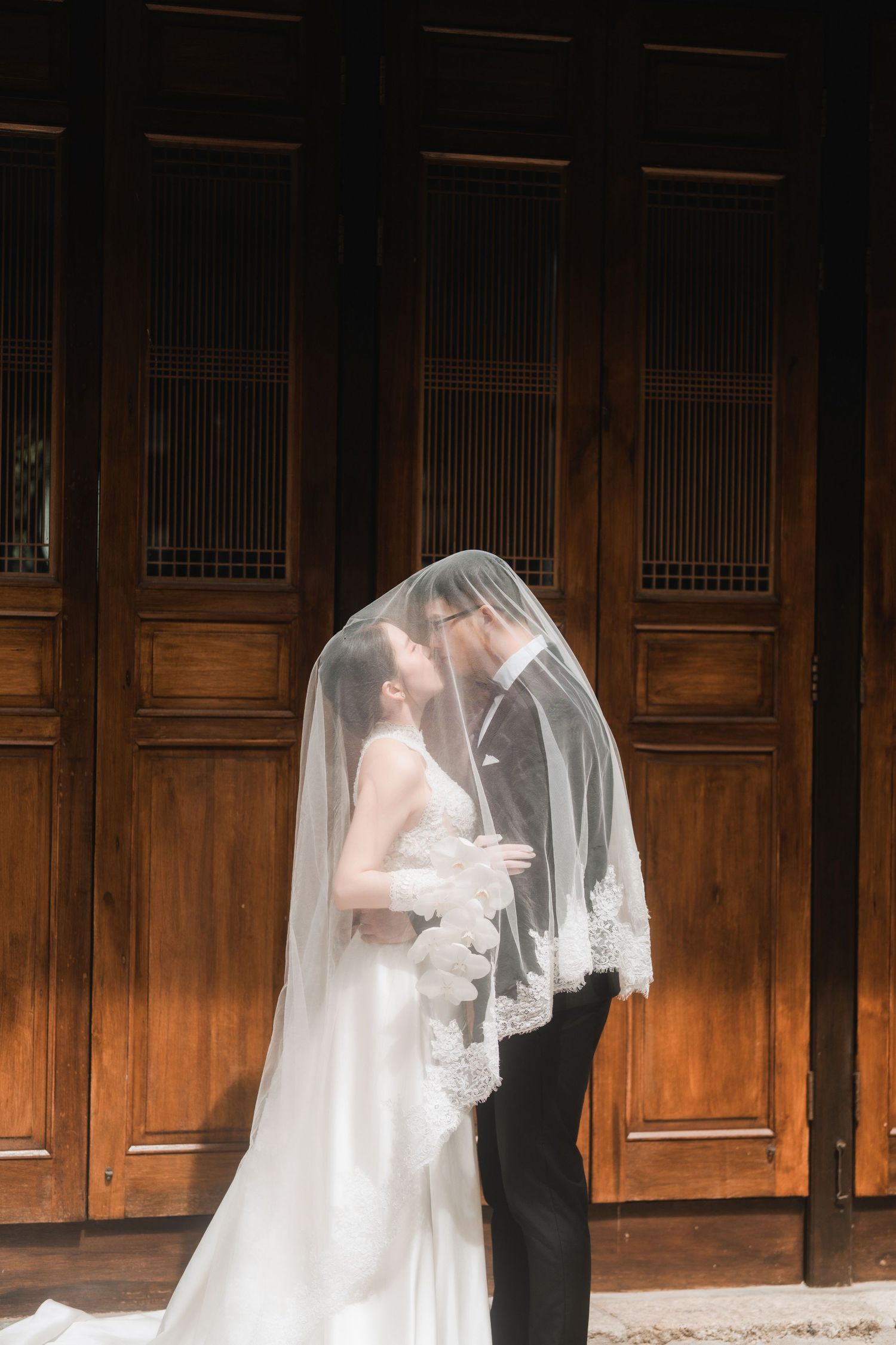 Artistic wedding photos in dark wooden hallway with dramatic lighting and shadows.