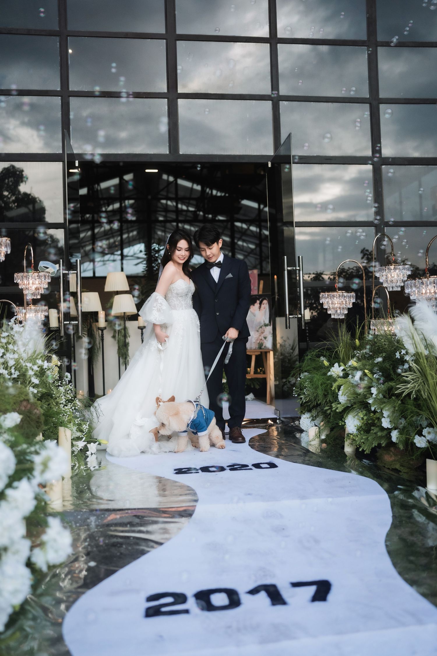 A wedding couple poses on blocks marked with years 2017 and 2020 in an elegant venue.