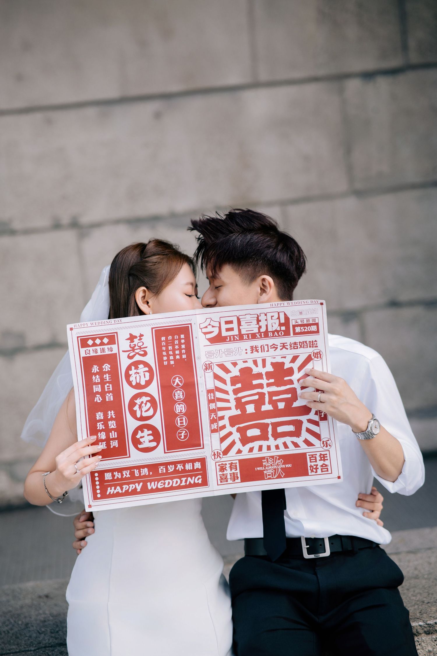 Couple holds red Chinese wedding signs while sharing romantic moments.