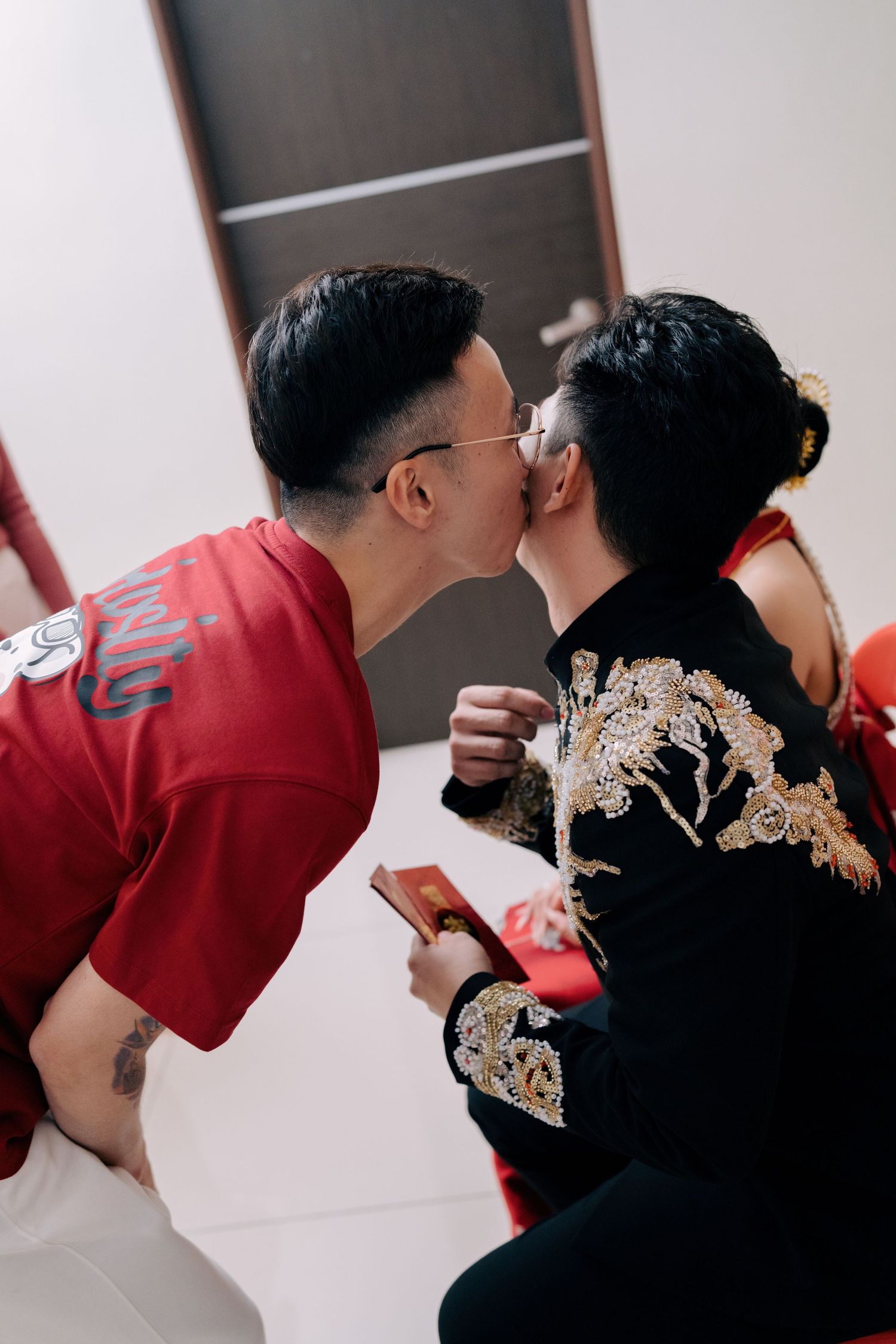 A guest jokingly kisses the groom's cheek during the traditional Chinese wedding celebrations