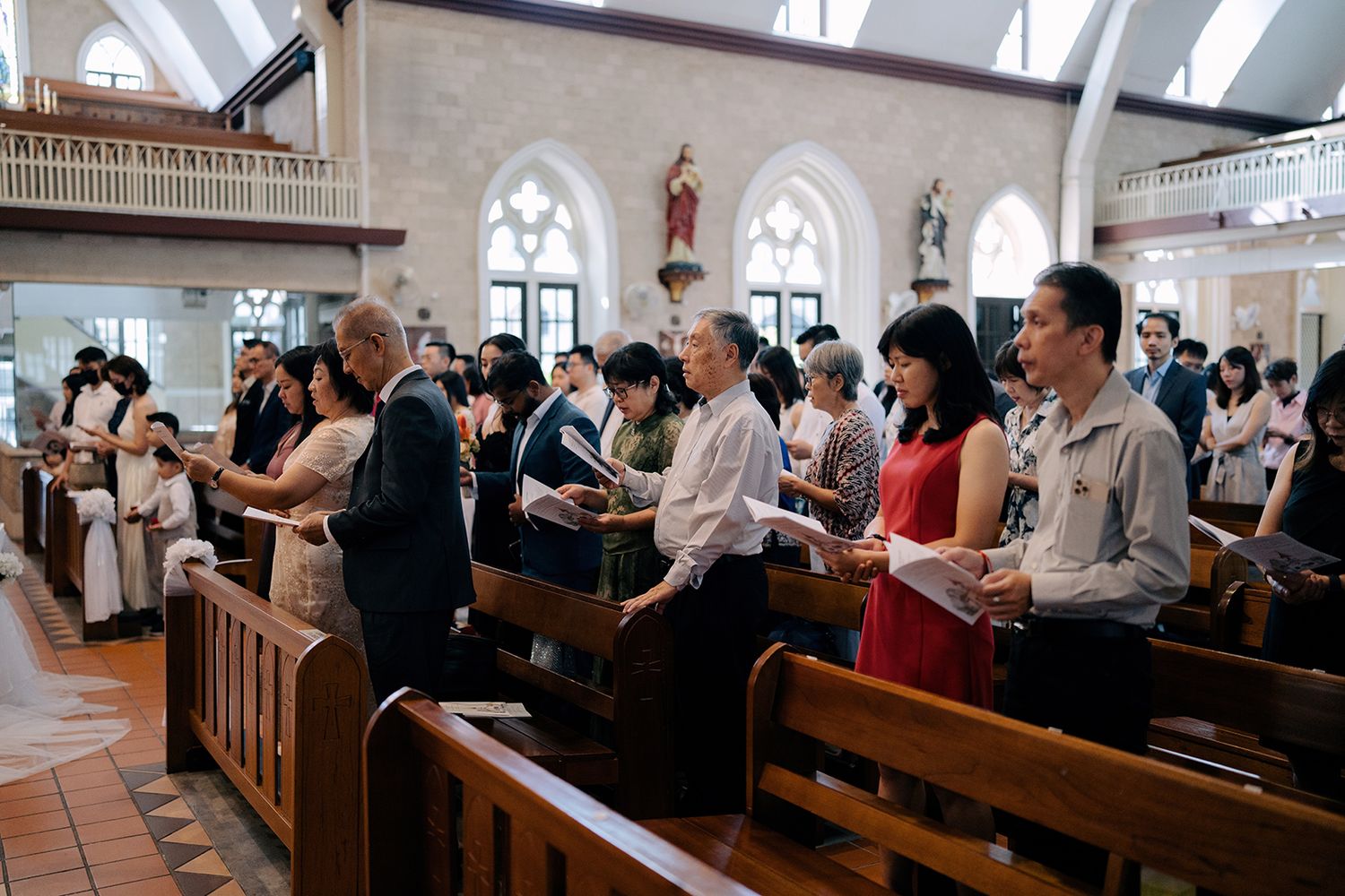 Wedding guests participating in a traditional church wedding ceremony while holding service programs