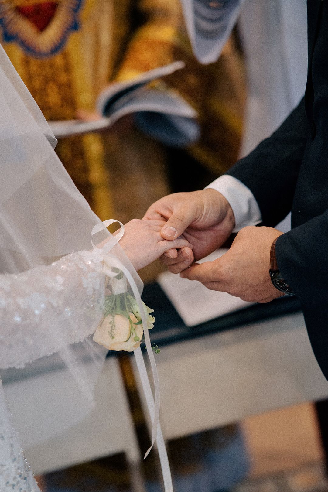 Close-up of hands exchanging rings during a wedding ceremony.
