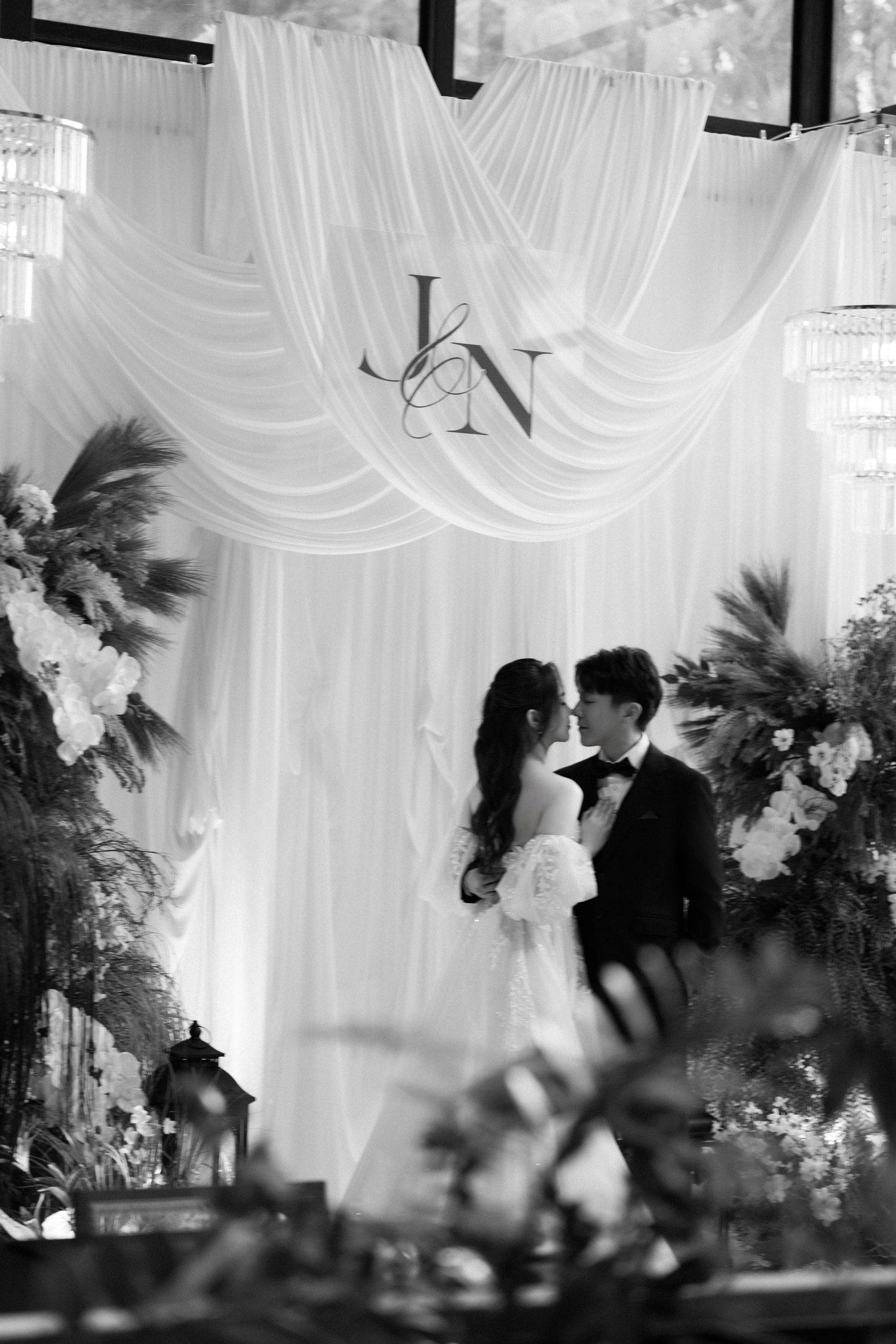 Black and white wedding reception scene with dramatic draping and floral decorations.