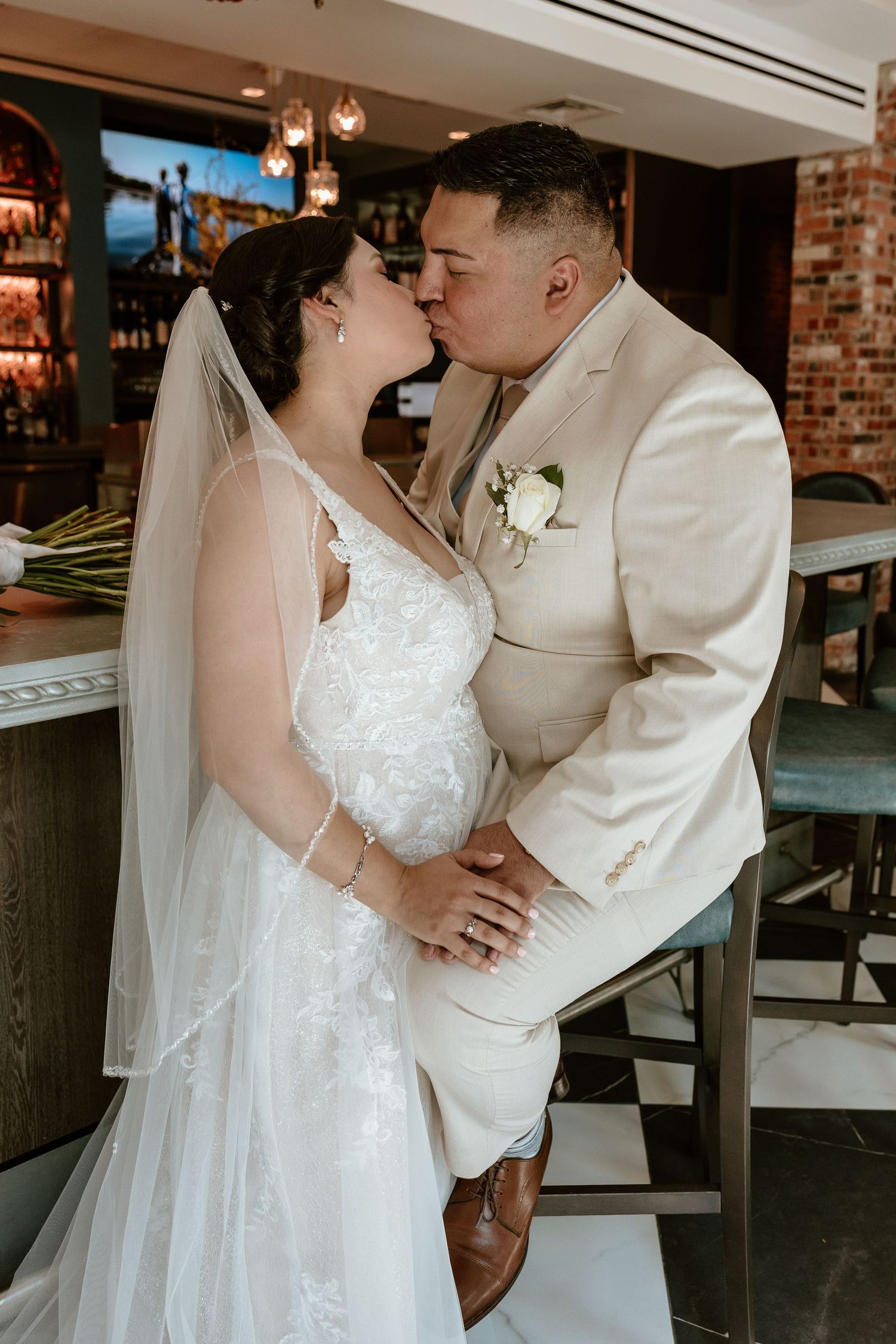 A romantic wedding moment captured in front of an exposed brick wall and checkered floor.