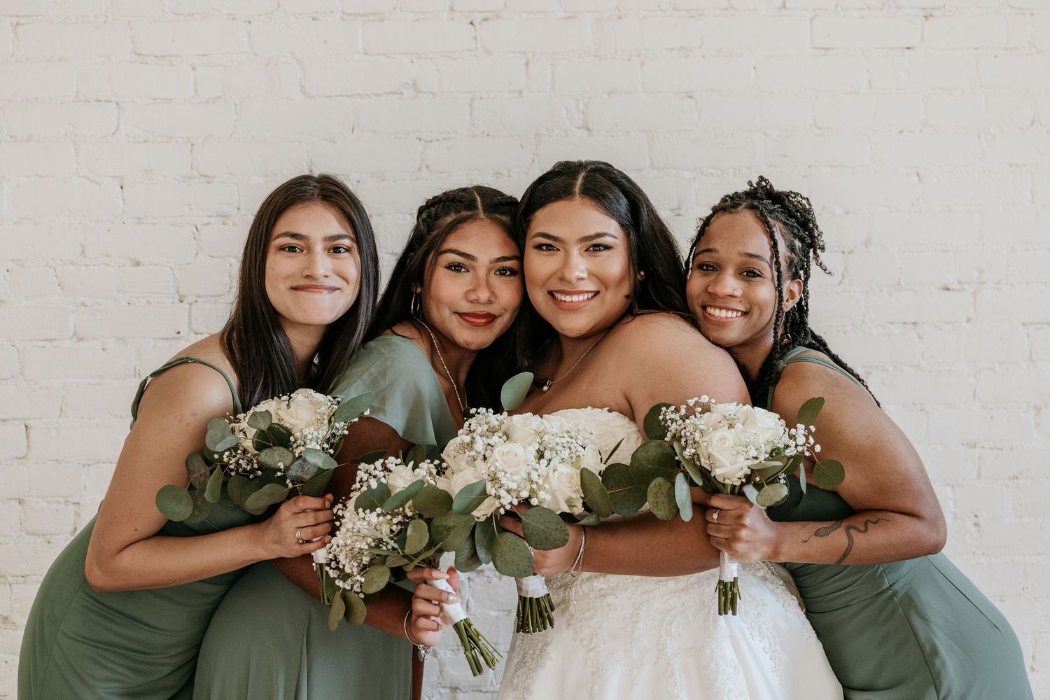 Bridal party smiles together in coordinated sage and white attire.