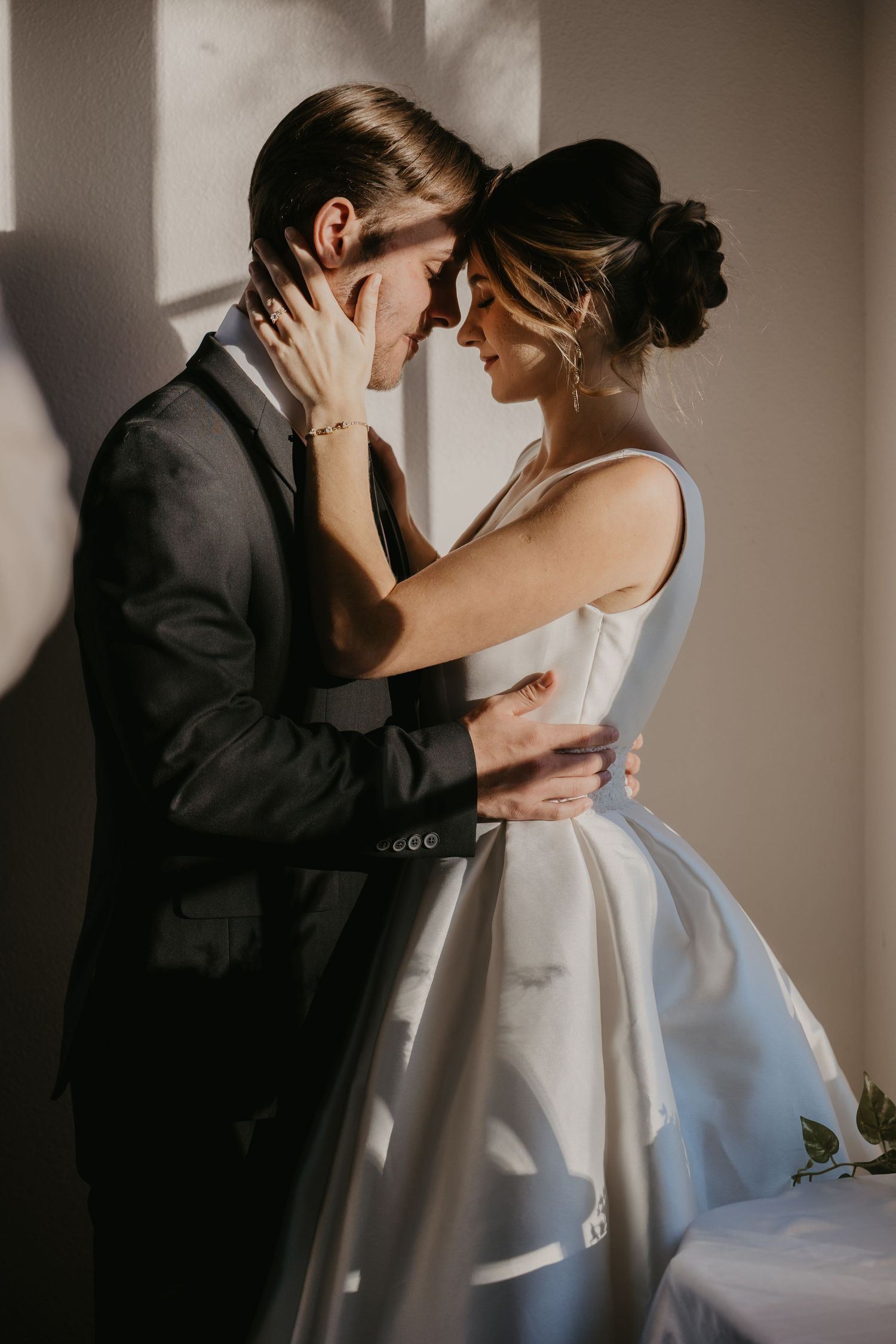 Intimate indoor wedding portraits with dramatic lighting and elegant formal attire.