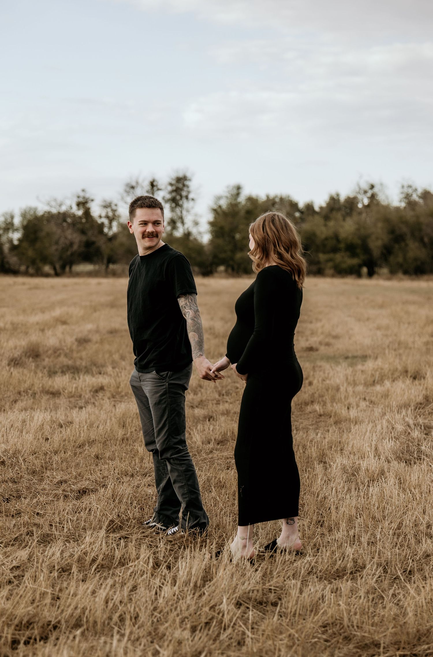 Couple standing in golden field during sunset photo session.