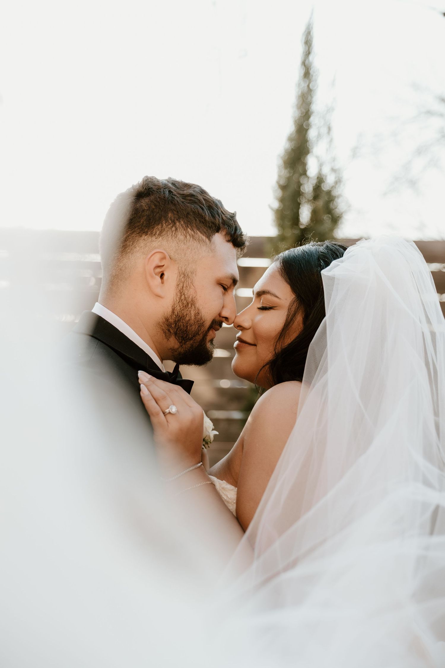 Romantic close-up of newlyweds sharing an intimate moment under bridal veil.
