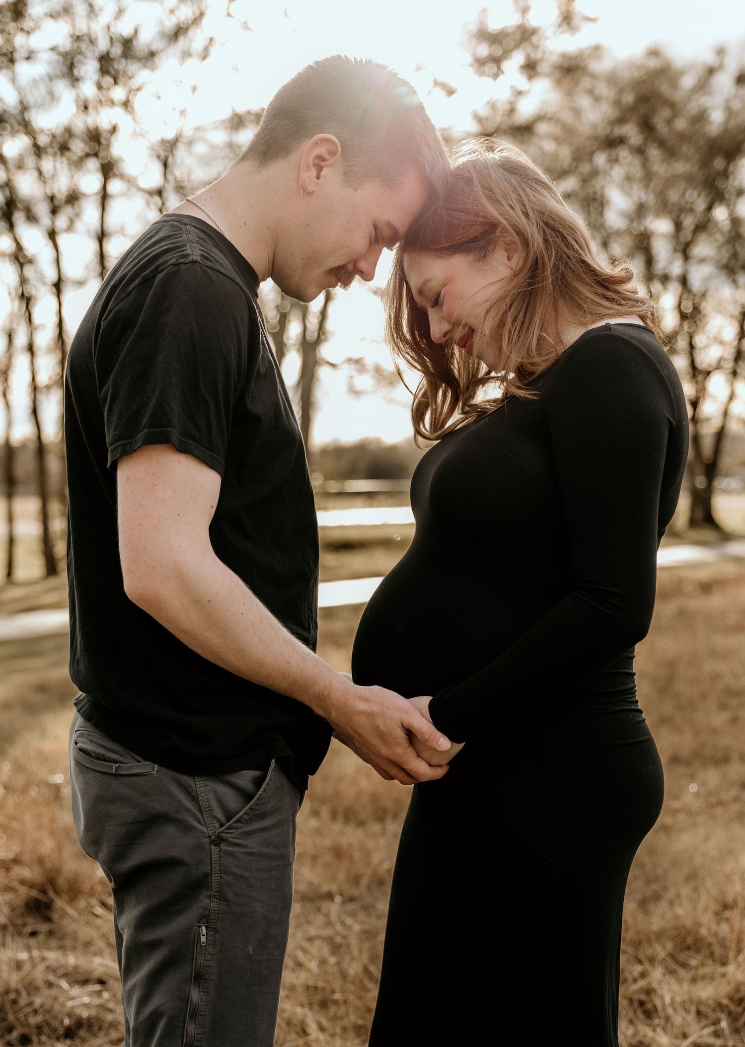 A tender maternity photo captures an intimate moment between a couple in nature.