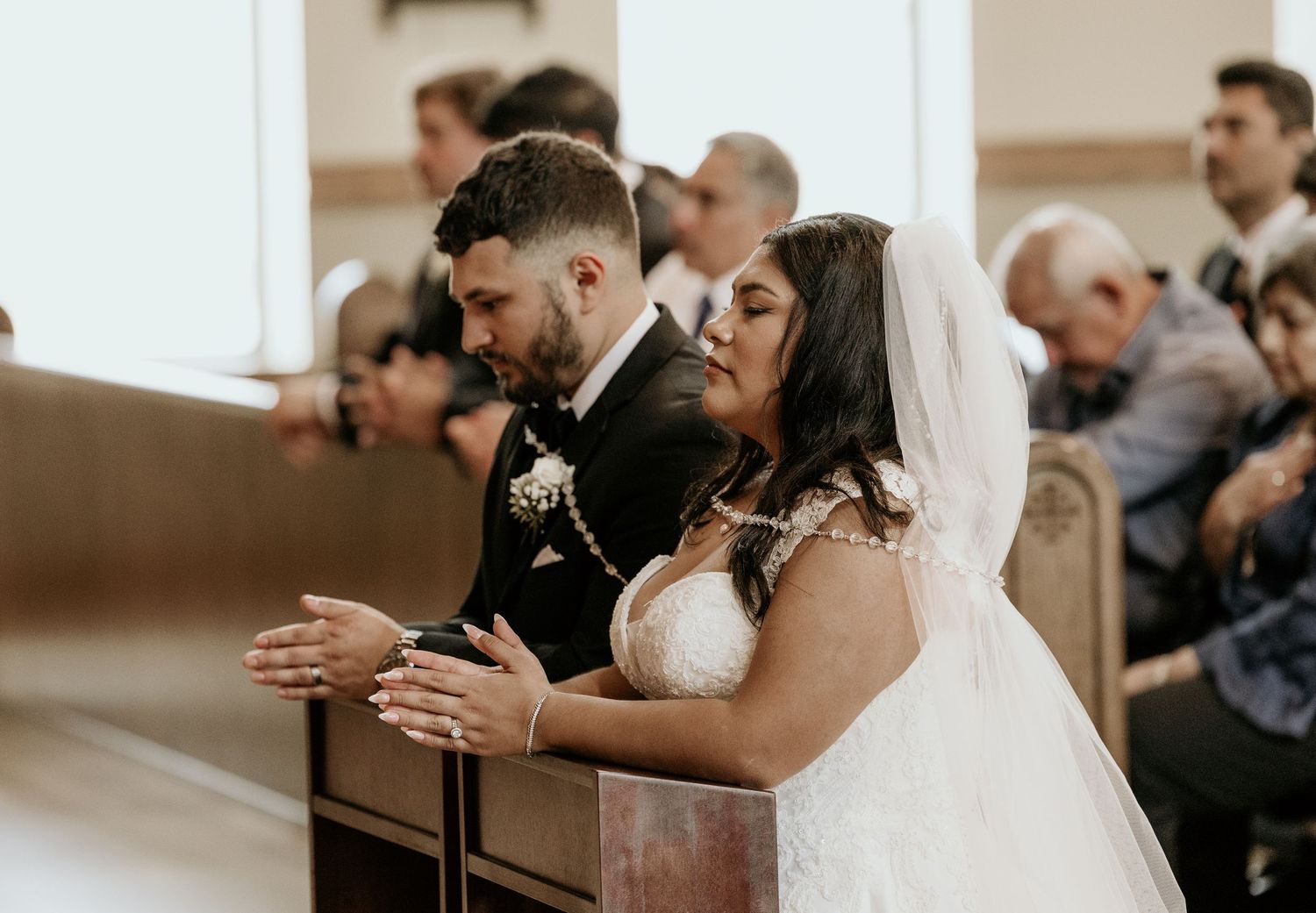 A couple praying together during their wedding ceremony in a church.