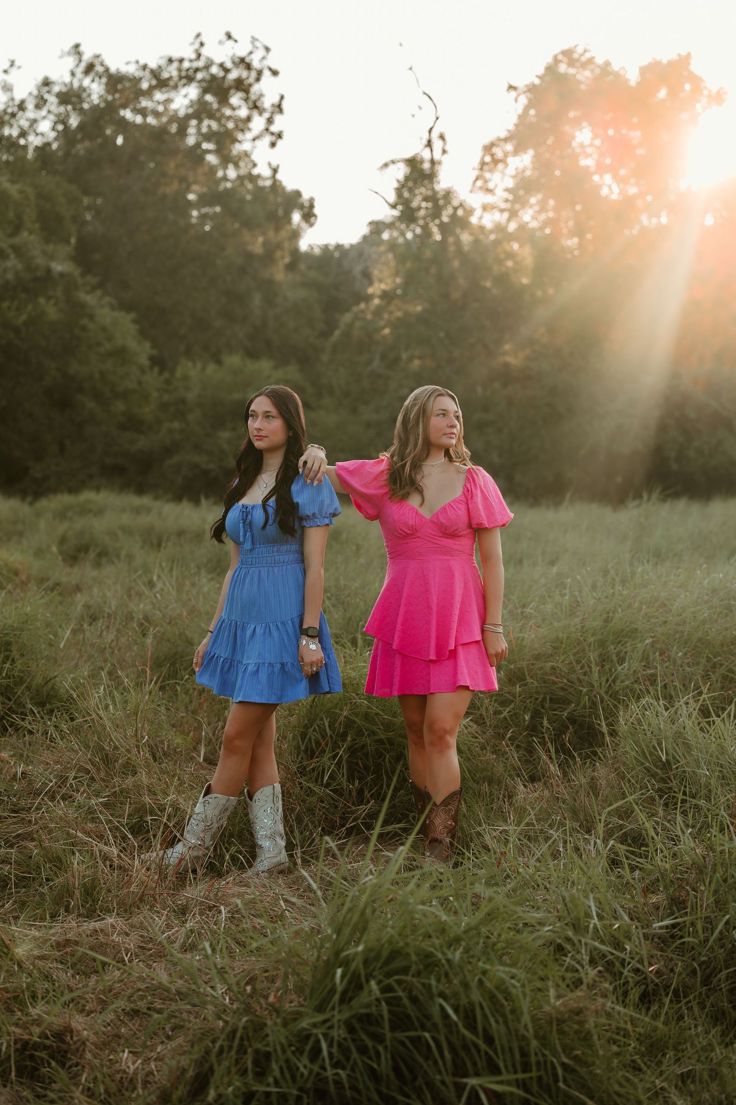 Best Friends in matching ruffled dresses pose together in a golden field at dusk.