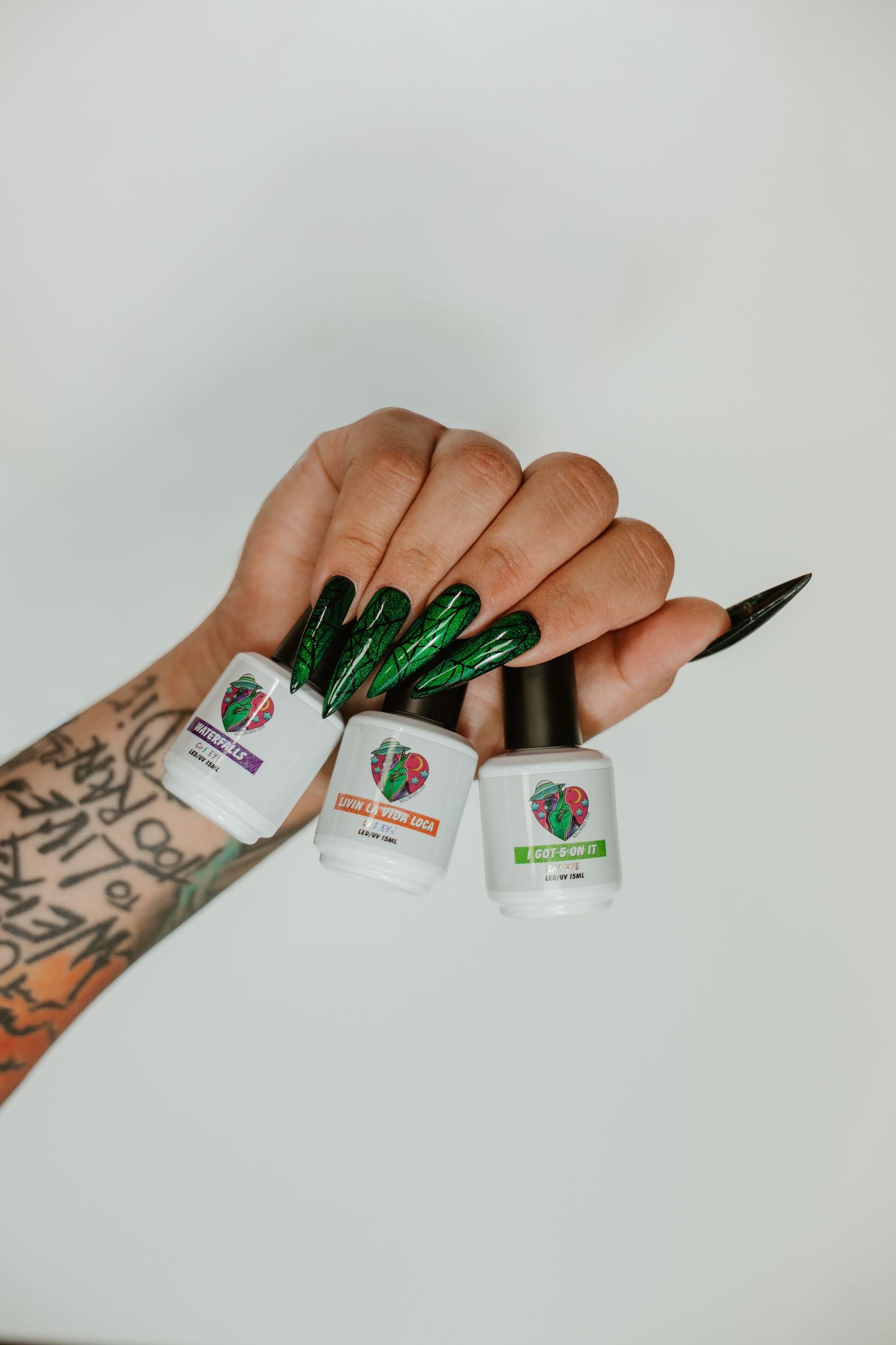 Nail artist branding with green metallic nails displaying nail polish bottles.