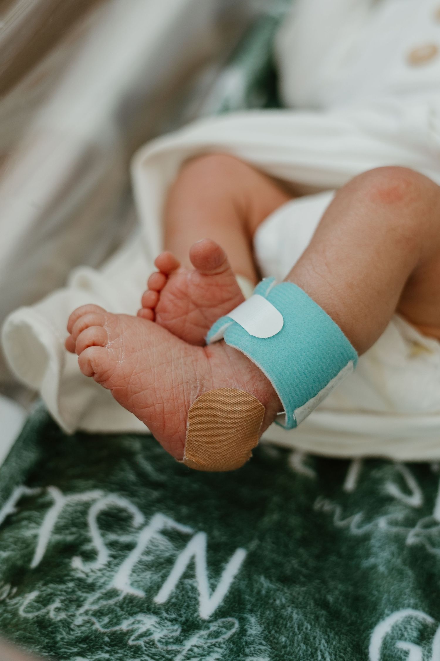 Close-up of tiny newborn feet with medical tags and bandages.