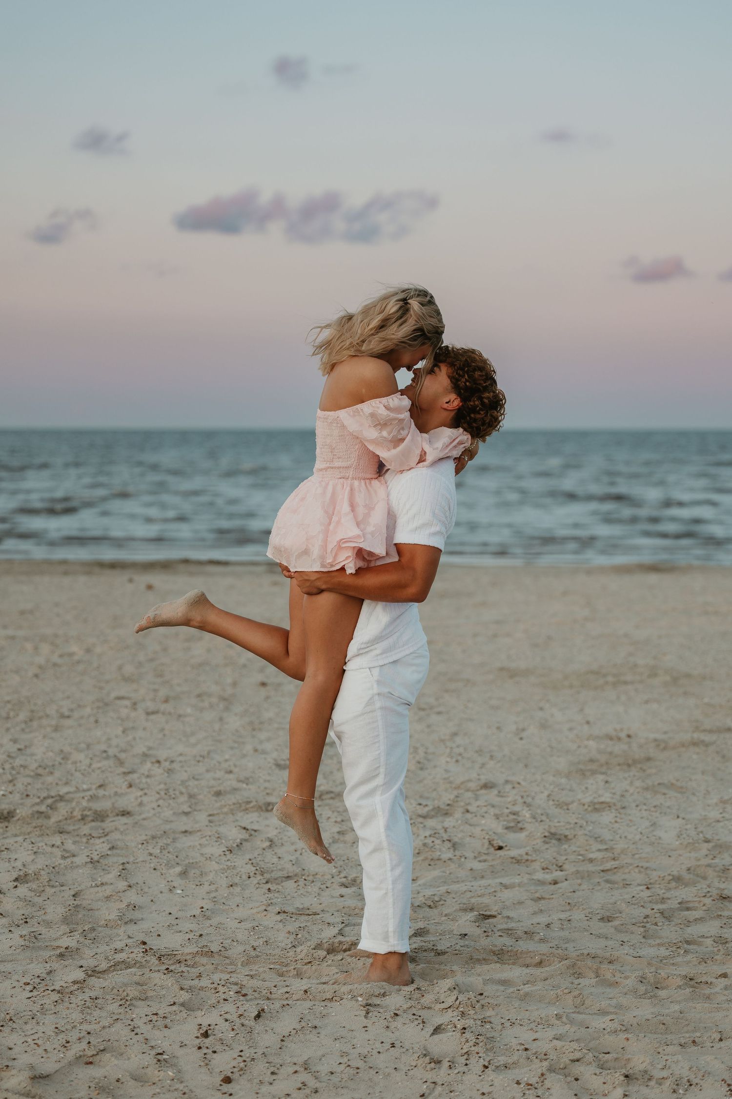 Romantic beach embrace at sunset with ocean waves in background.