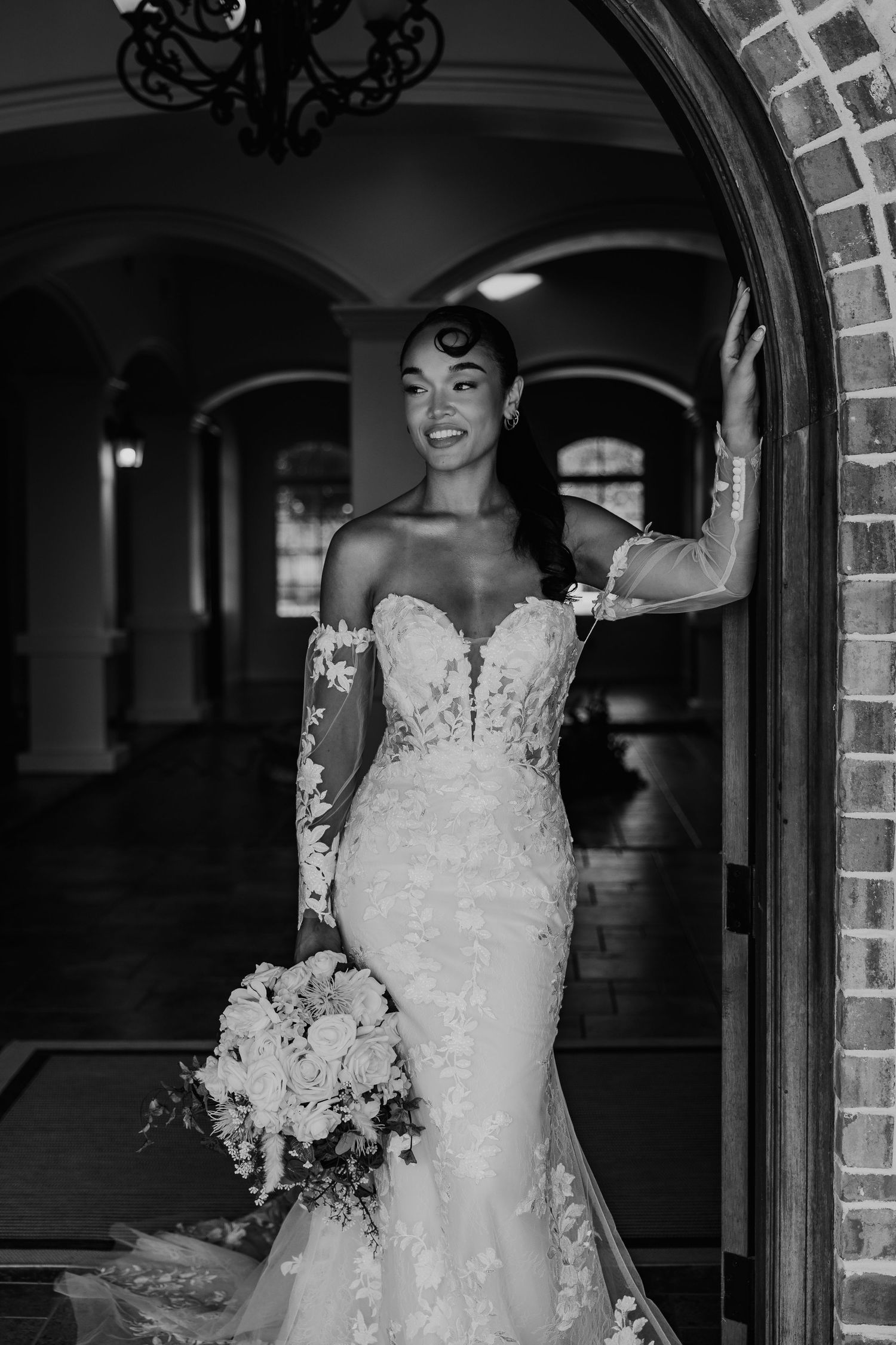 Black and white wedding portrait under brick archway with elegant lace dress from Lacy Bridal in San Antonio, TX.