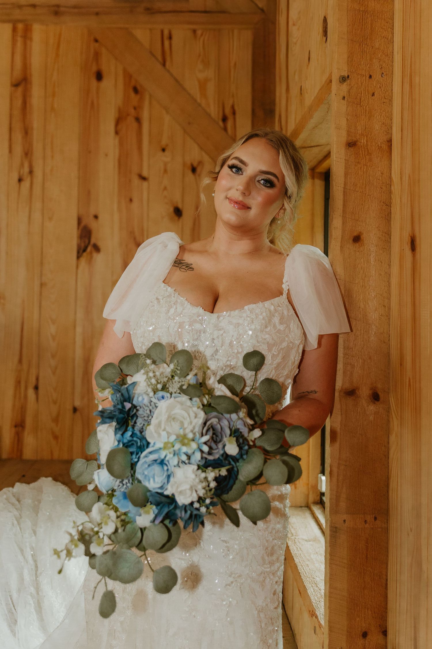 Beautiful wedding bouquet featuring blue and white flowers with eucalyptus leaves against rustic wooden walls.