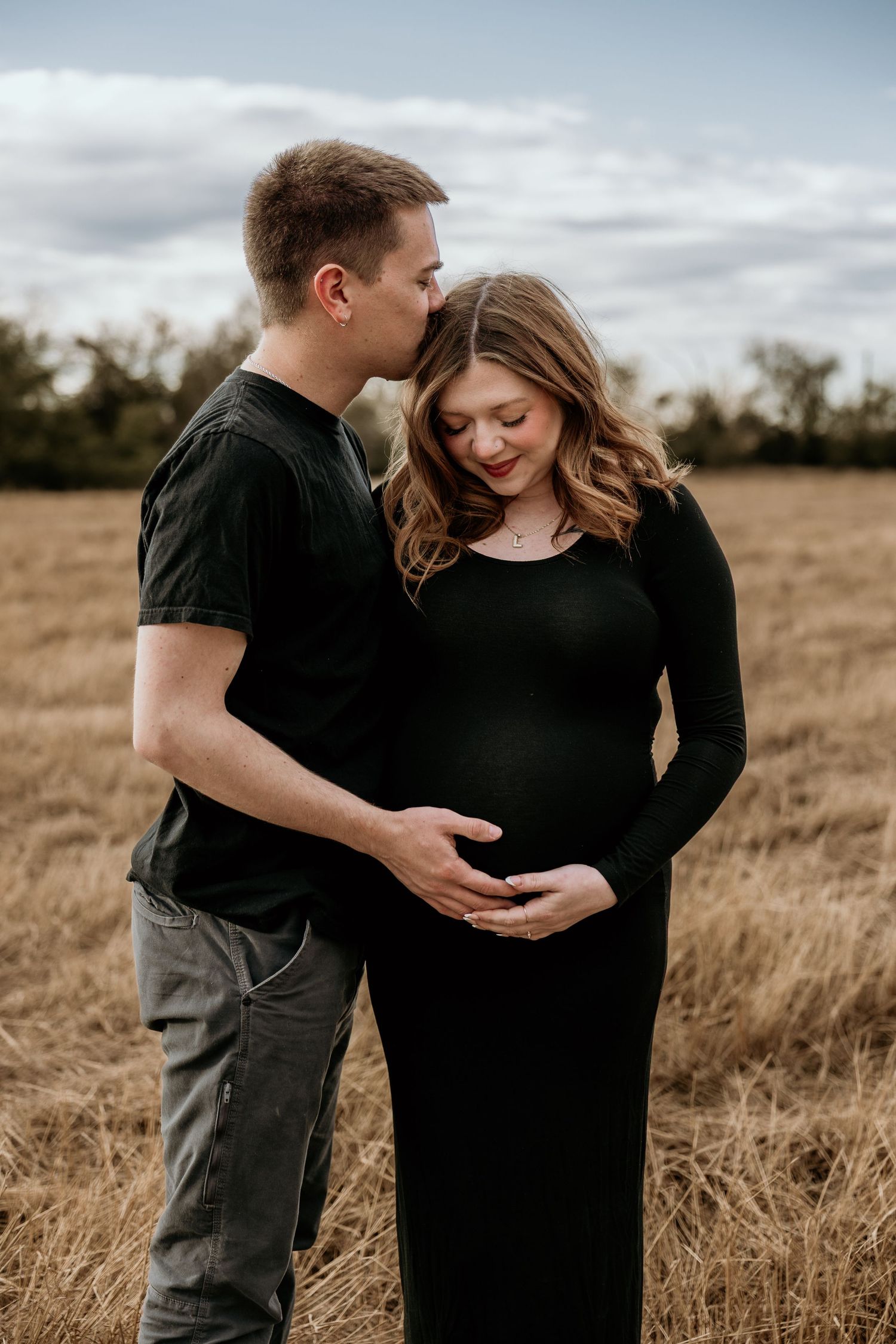 Intimate maternity photo of couple embracing in field.