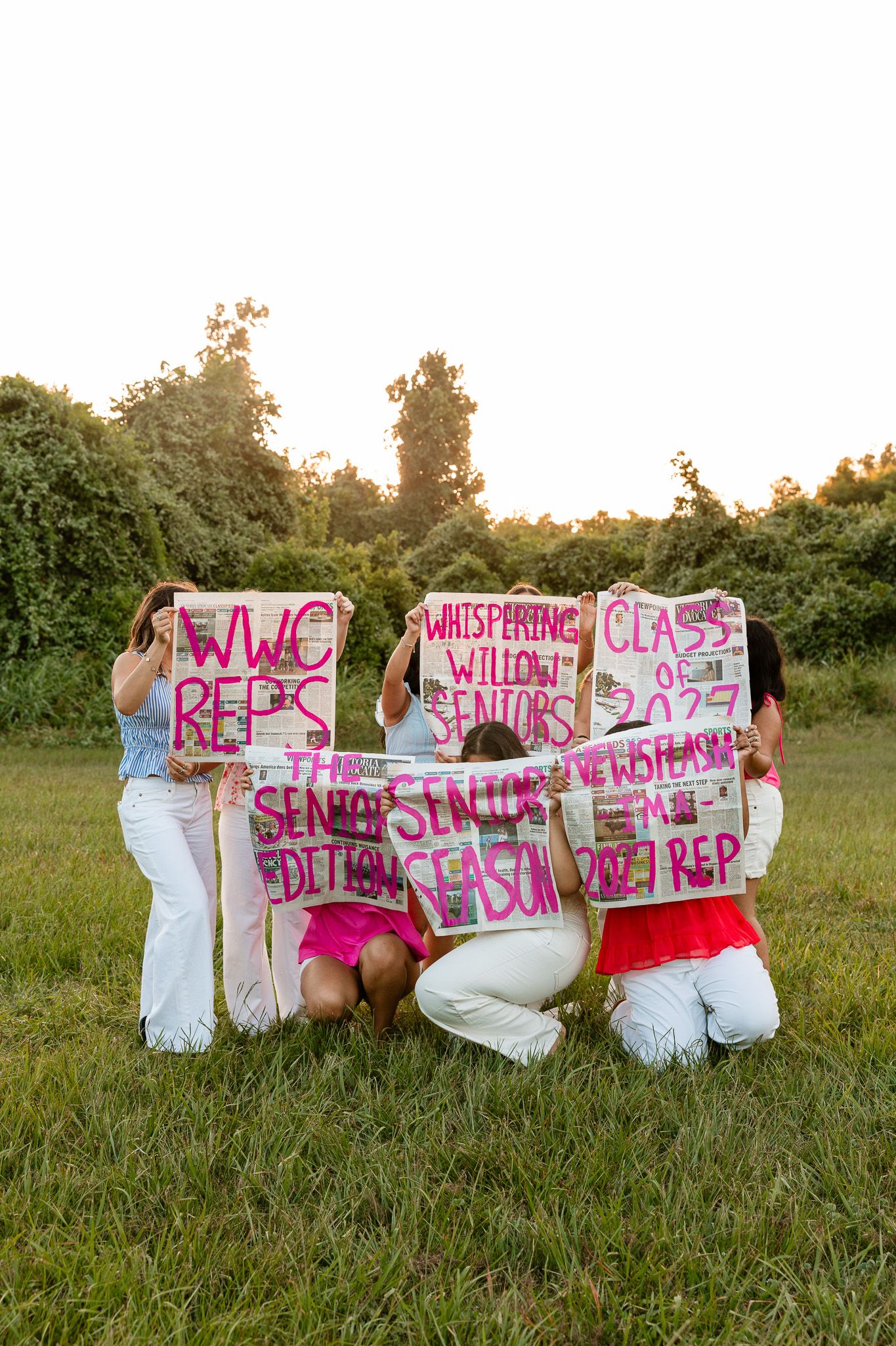 Group of girls holding signs reading WWC Reps, Whispering Willow Seniors, and Class of 2025 outdoors.