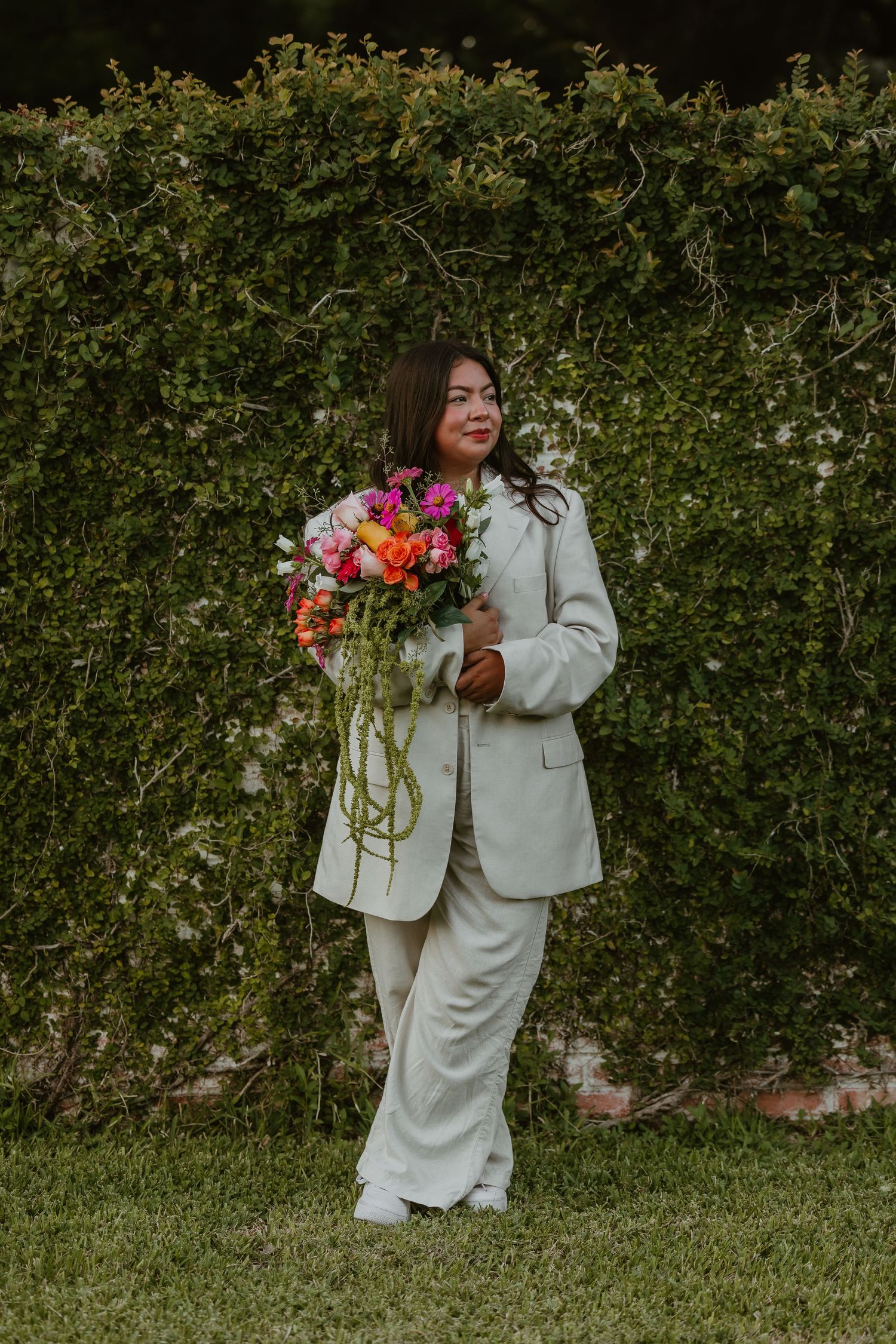 Outdoor portrait series with cream colored suit and vibrant floral arrangement.