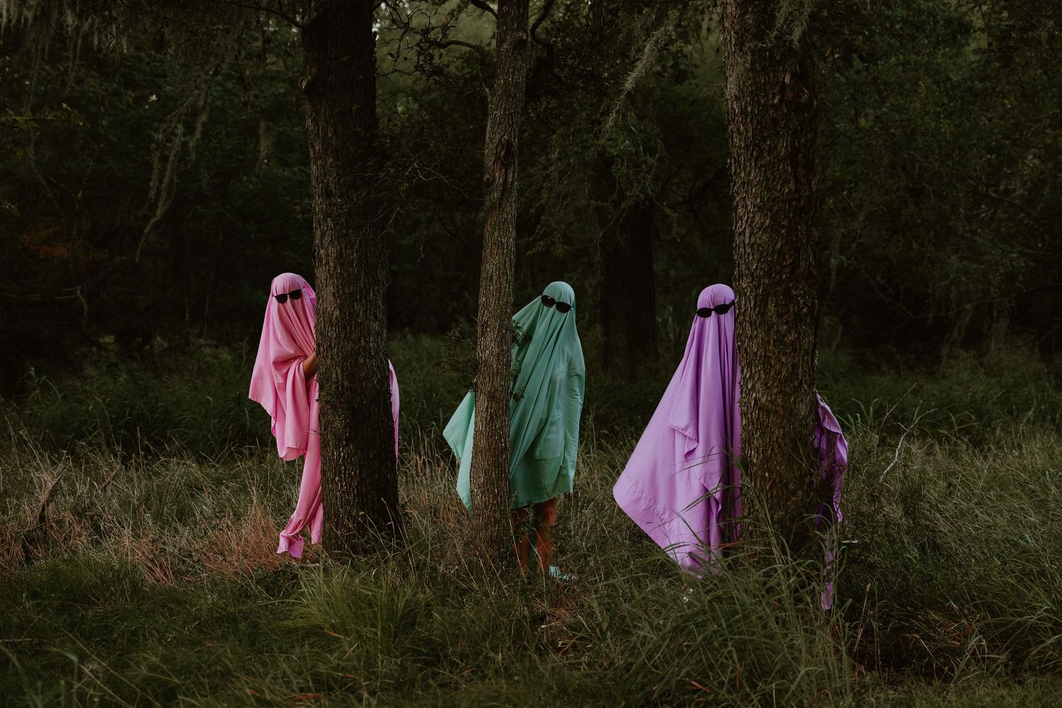 3 colorful ghosts hiding in the woods for a spooky photoshoot.