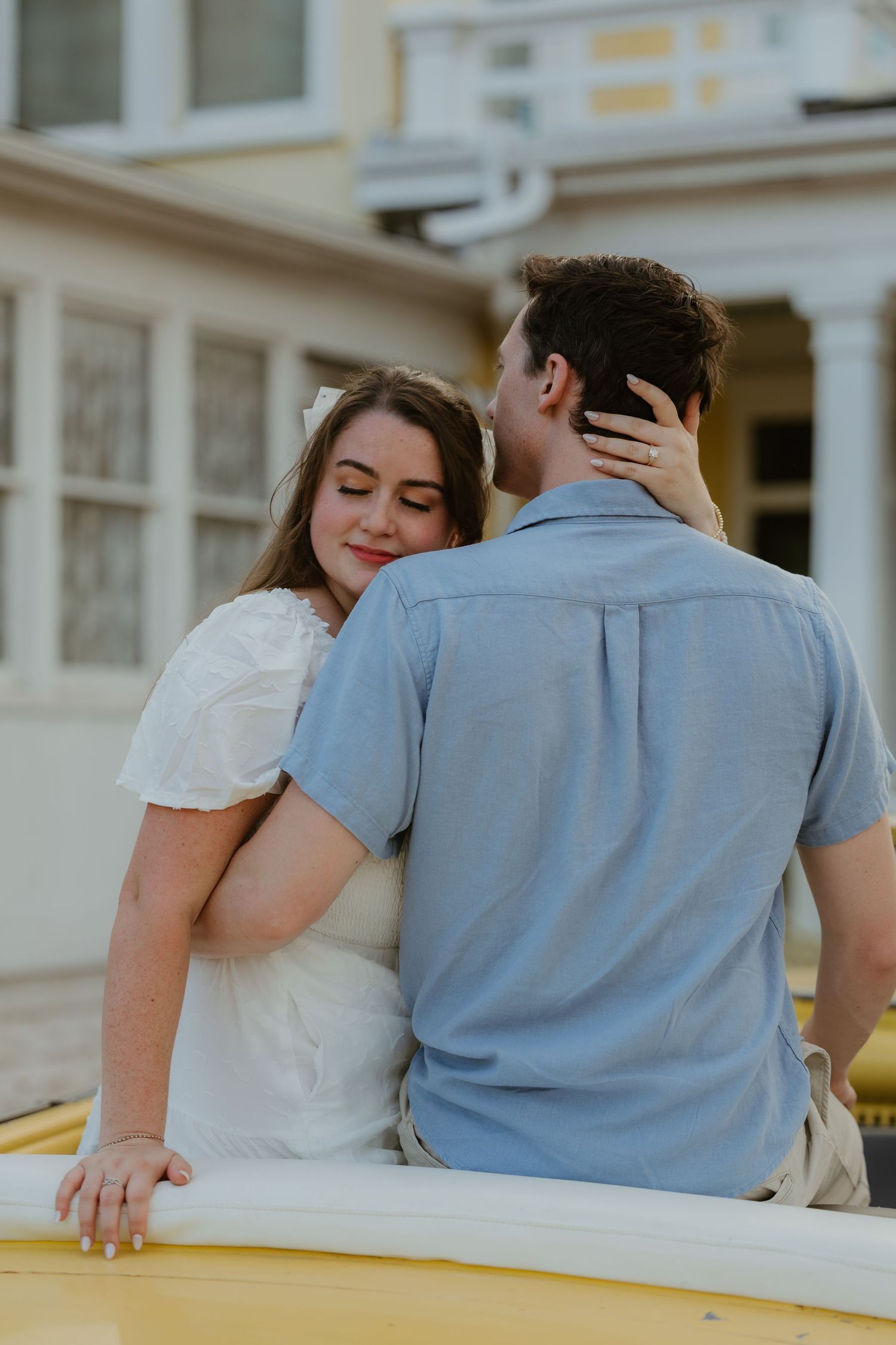 A tender moment between a couple on a yellow vintage automobile.