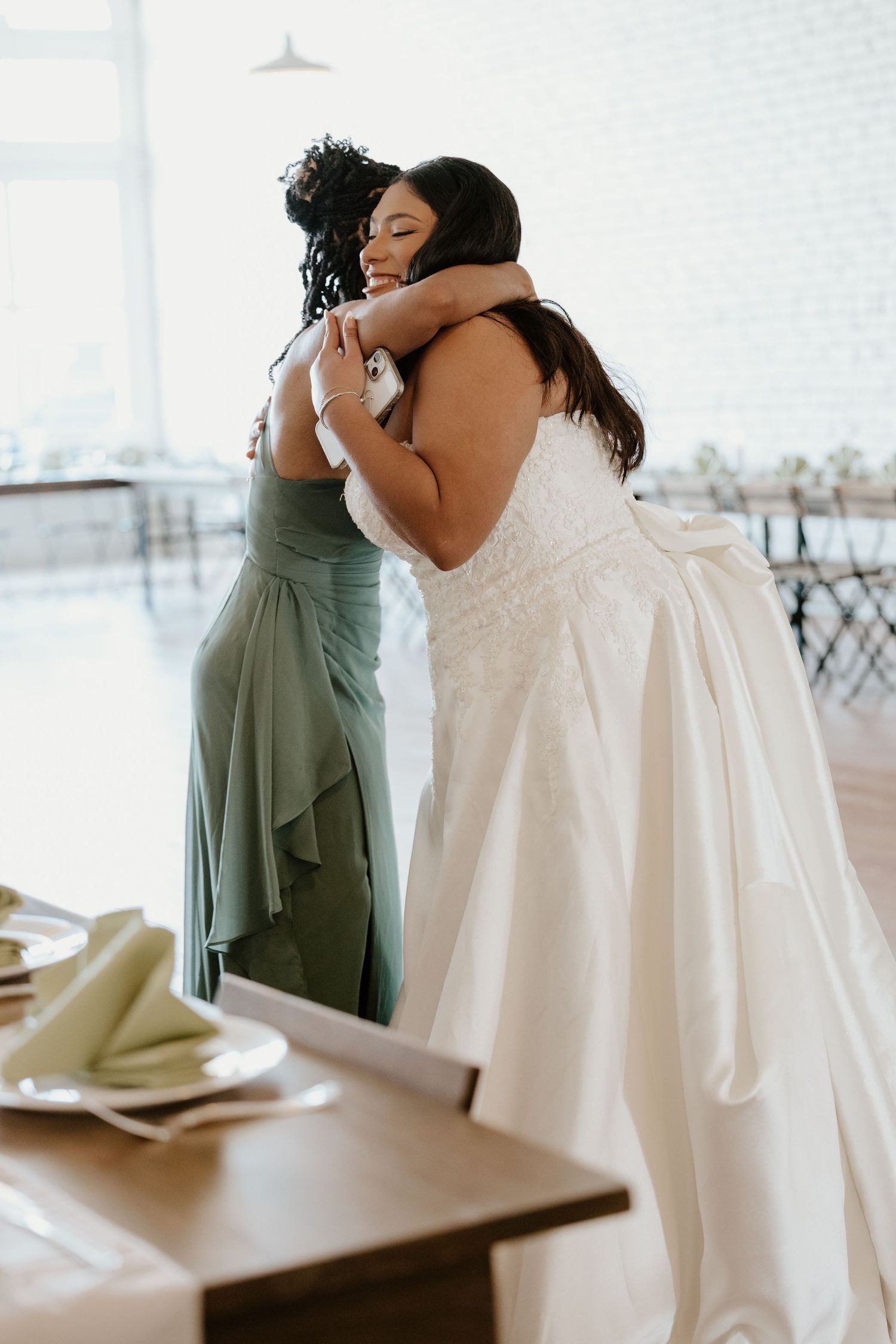 Emotional embraces between bride and bridesmaids in sage green dresses.