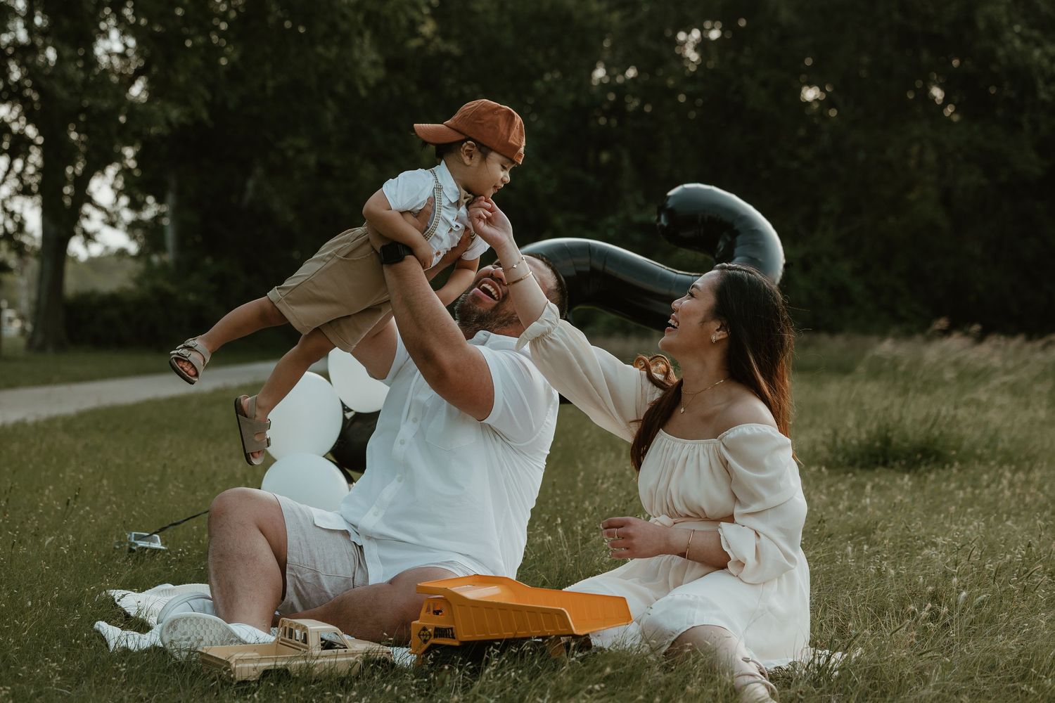 Family having a playful picnic outdoors with question mark balloons and toys.