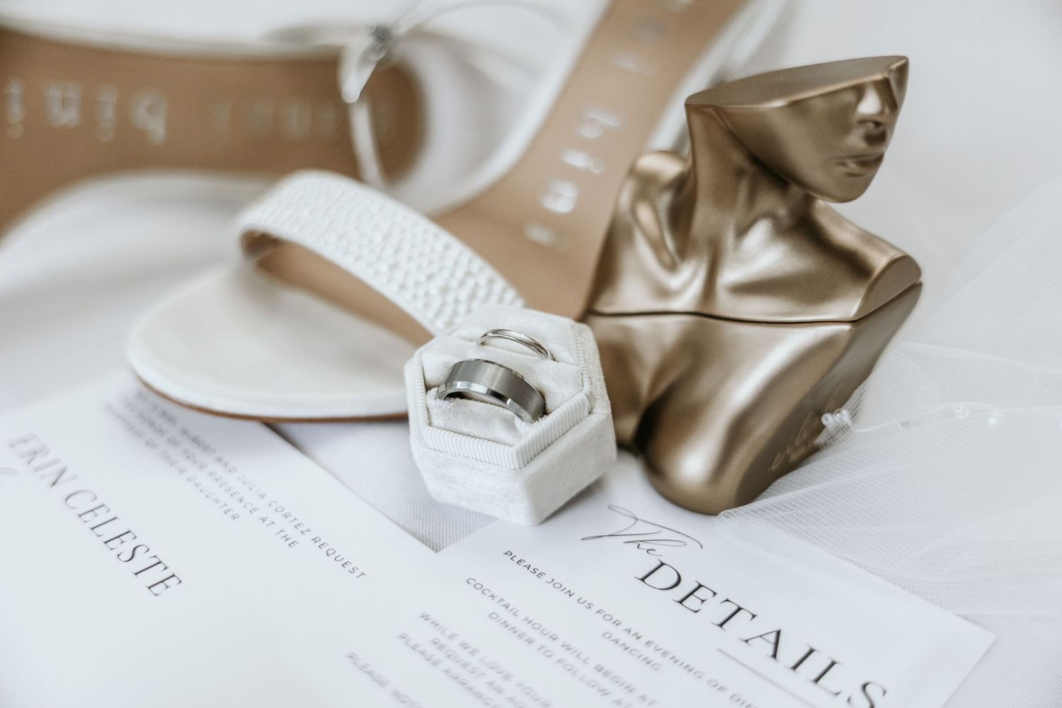 Pearl wedding shoes, white ring box and wedding day perfume along with classic white wedding RSVP cards.