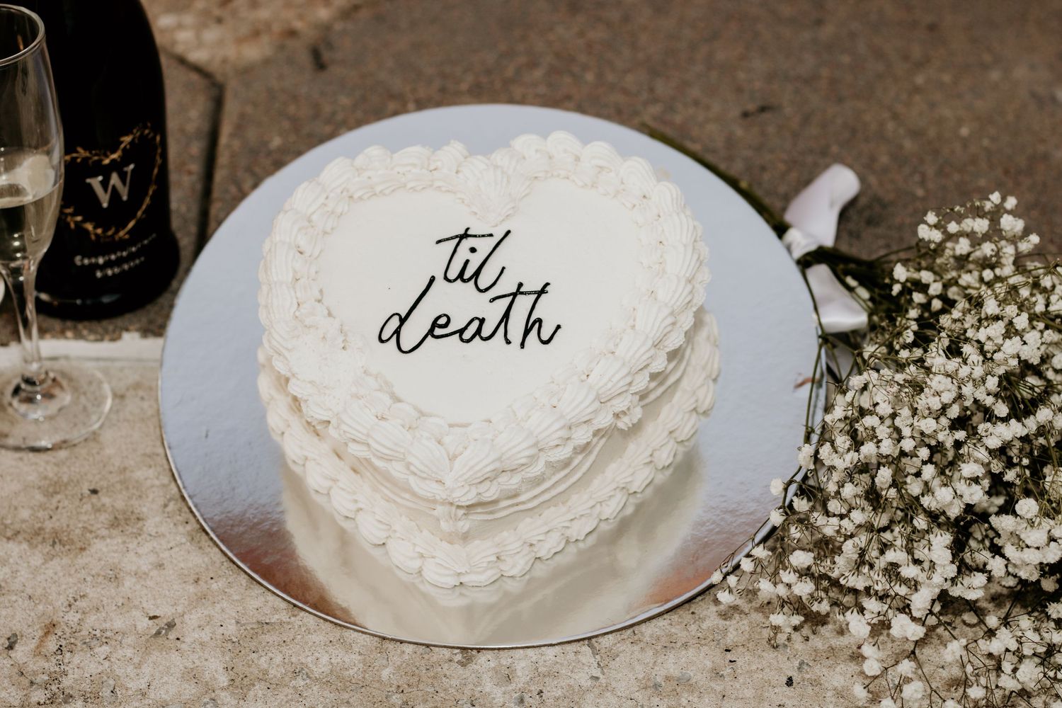 A close-up of a heart-shaped white wedding cake decorated with script writing.