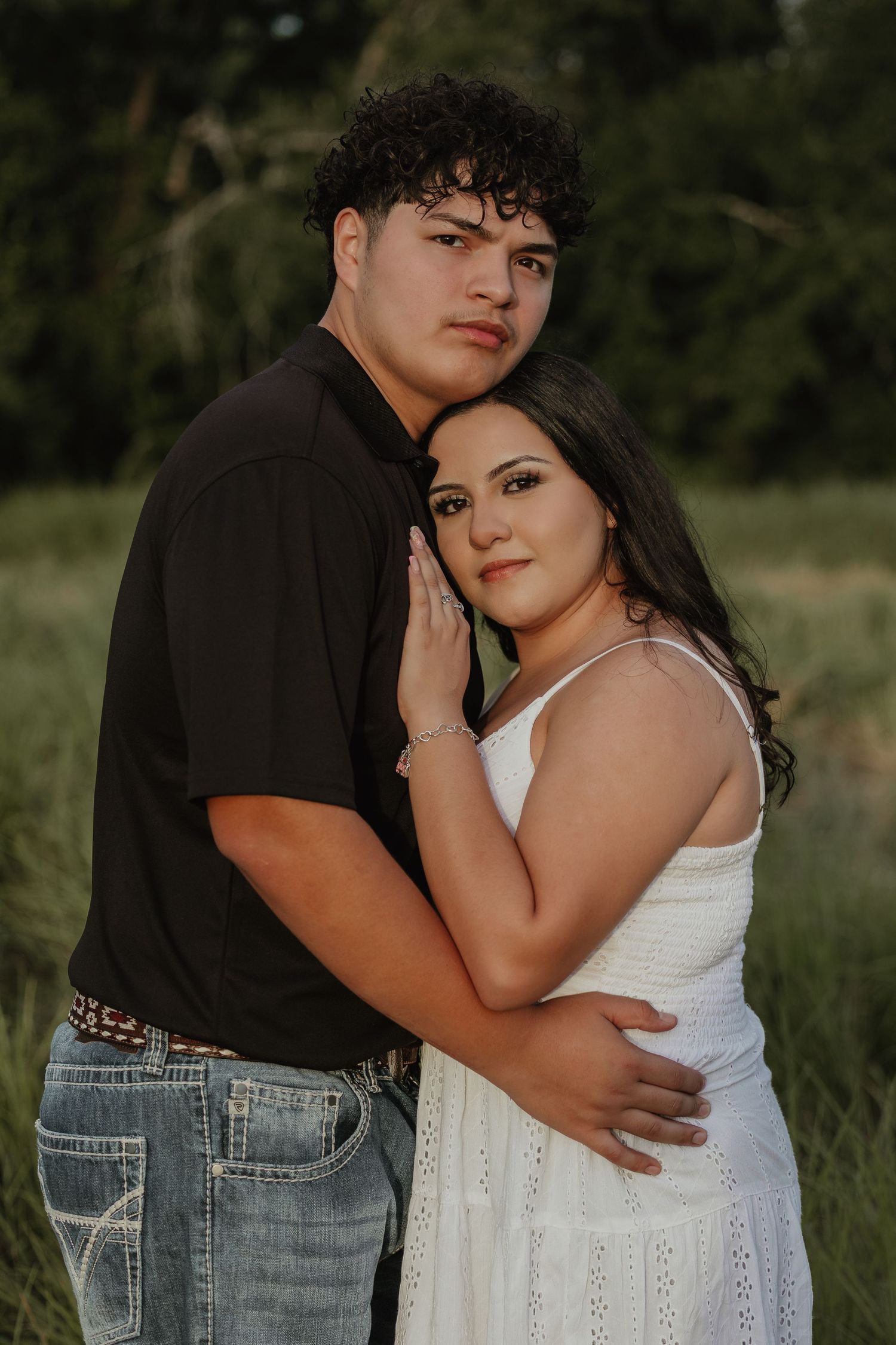 Intimate portrait of couple sharing close moment in field during sunset.