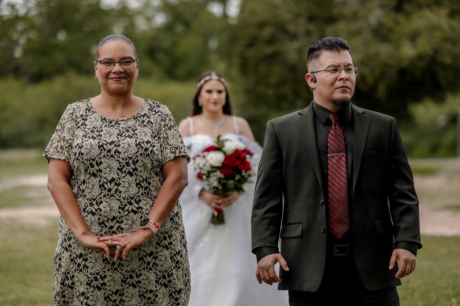 Wedding ceremony in progress on a green lawn with attendees in formal attire.