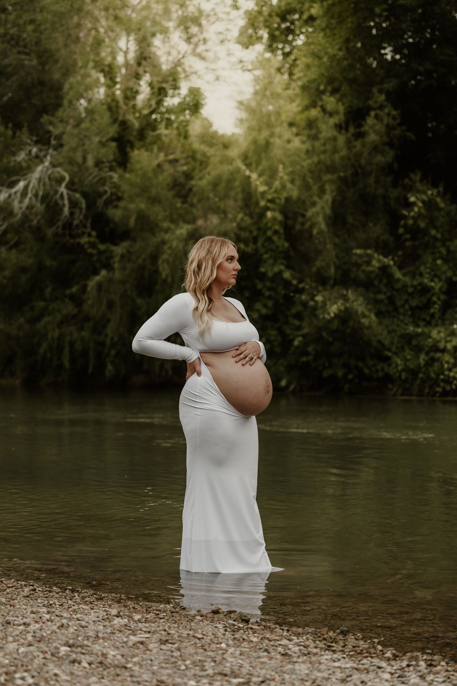 An artistic maternity portrait taken at the edge of a serene lake.
