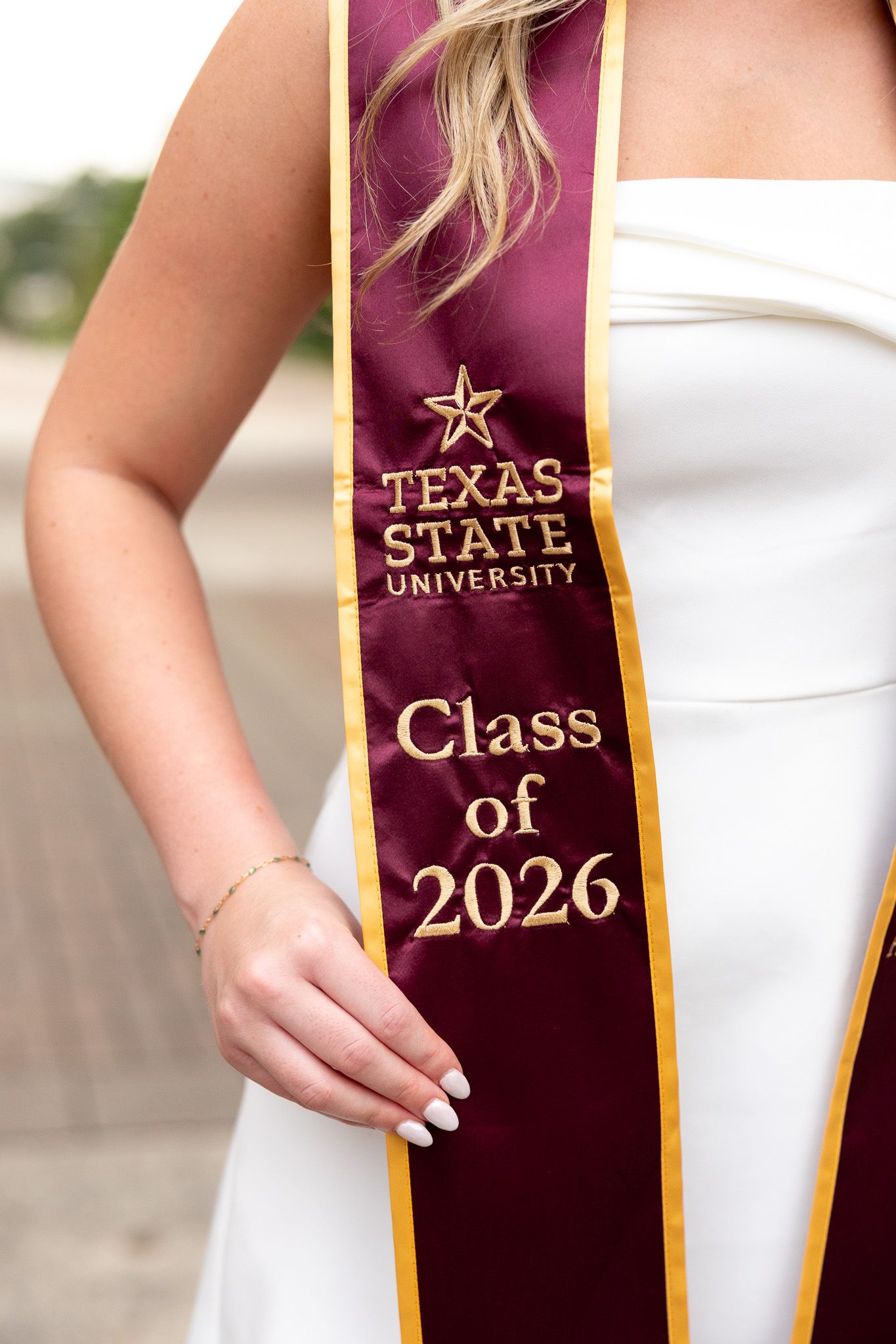 Texas State University Class of 2026 graduation sash worn by a student in a white dress.