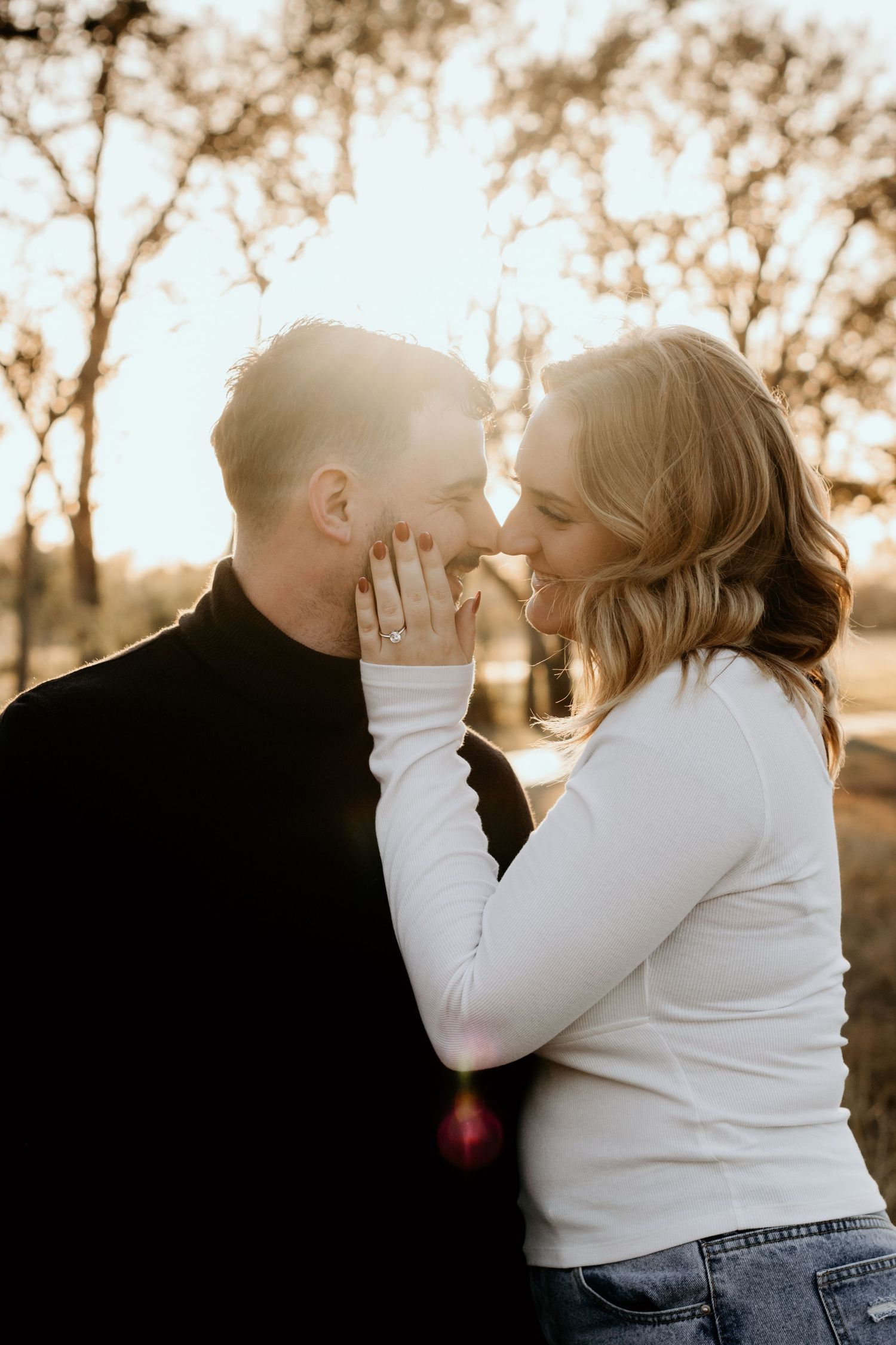 Intimate couple sharing a tender moment outdoors during golden hour after engagement.