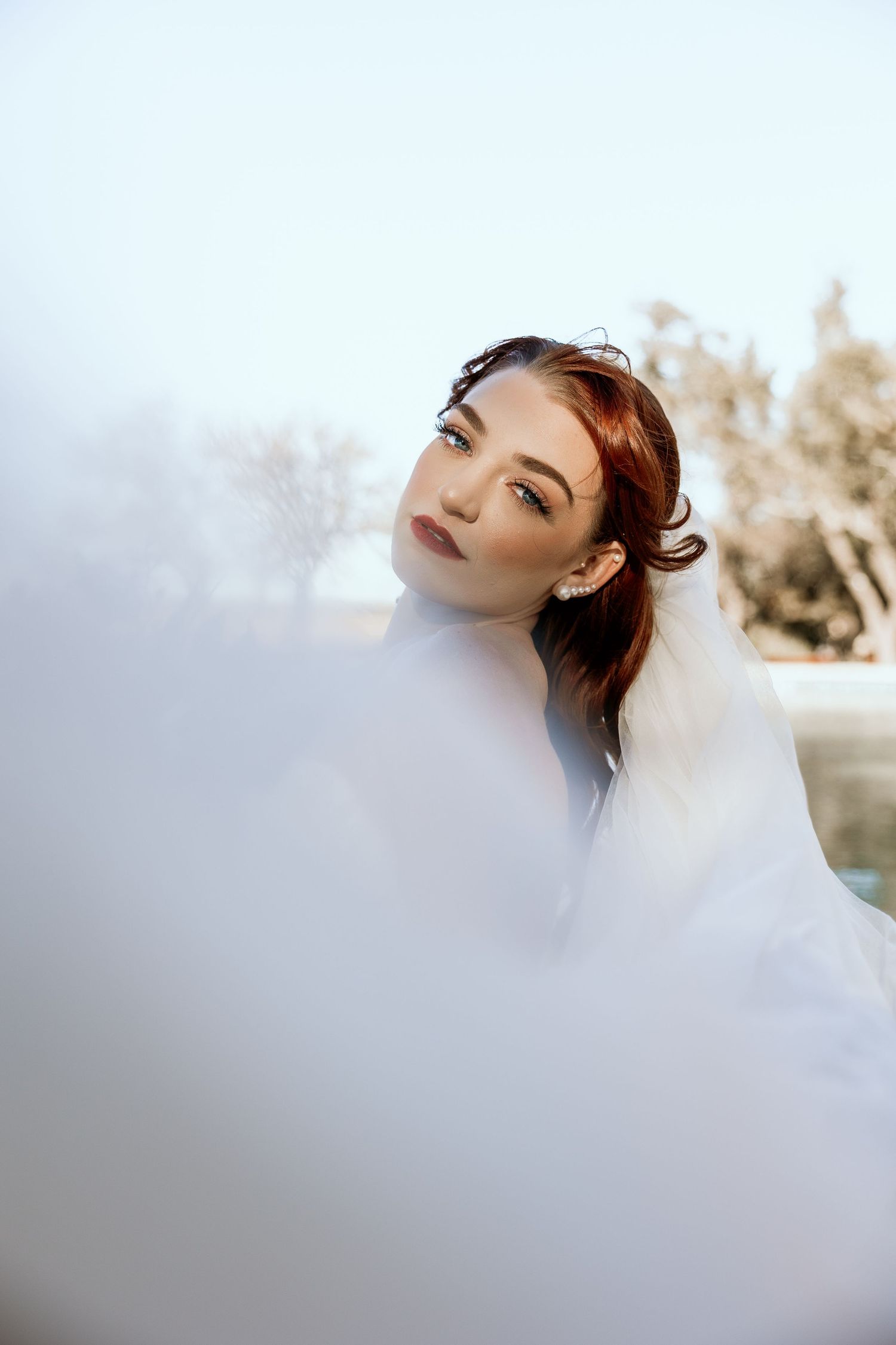 Artistic bridal portrait with ethereal white veil creating a dreamy effect.