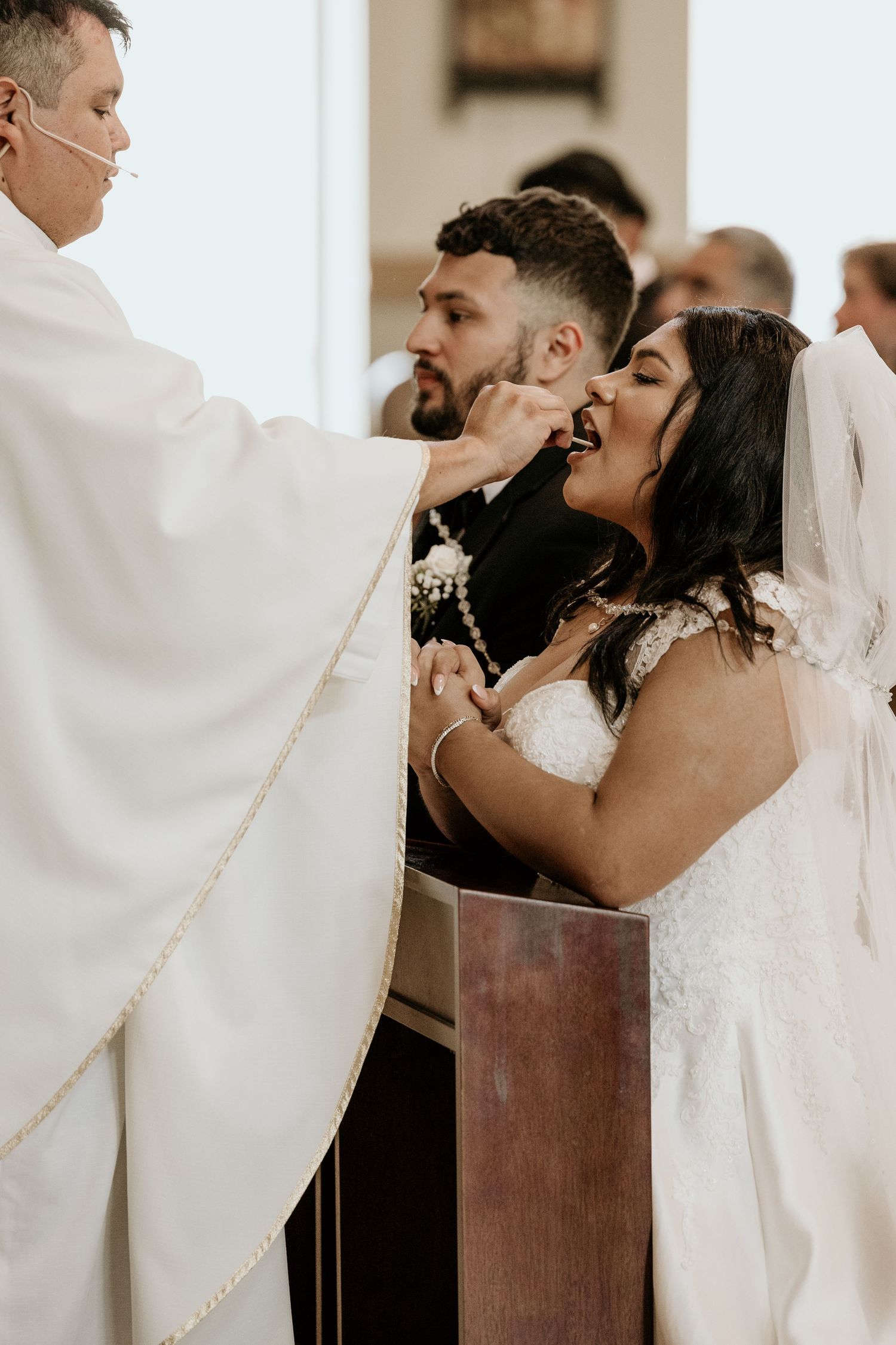 A priest administering communion to a couple during their wedding ceremony.