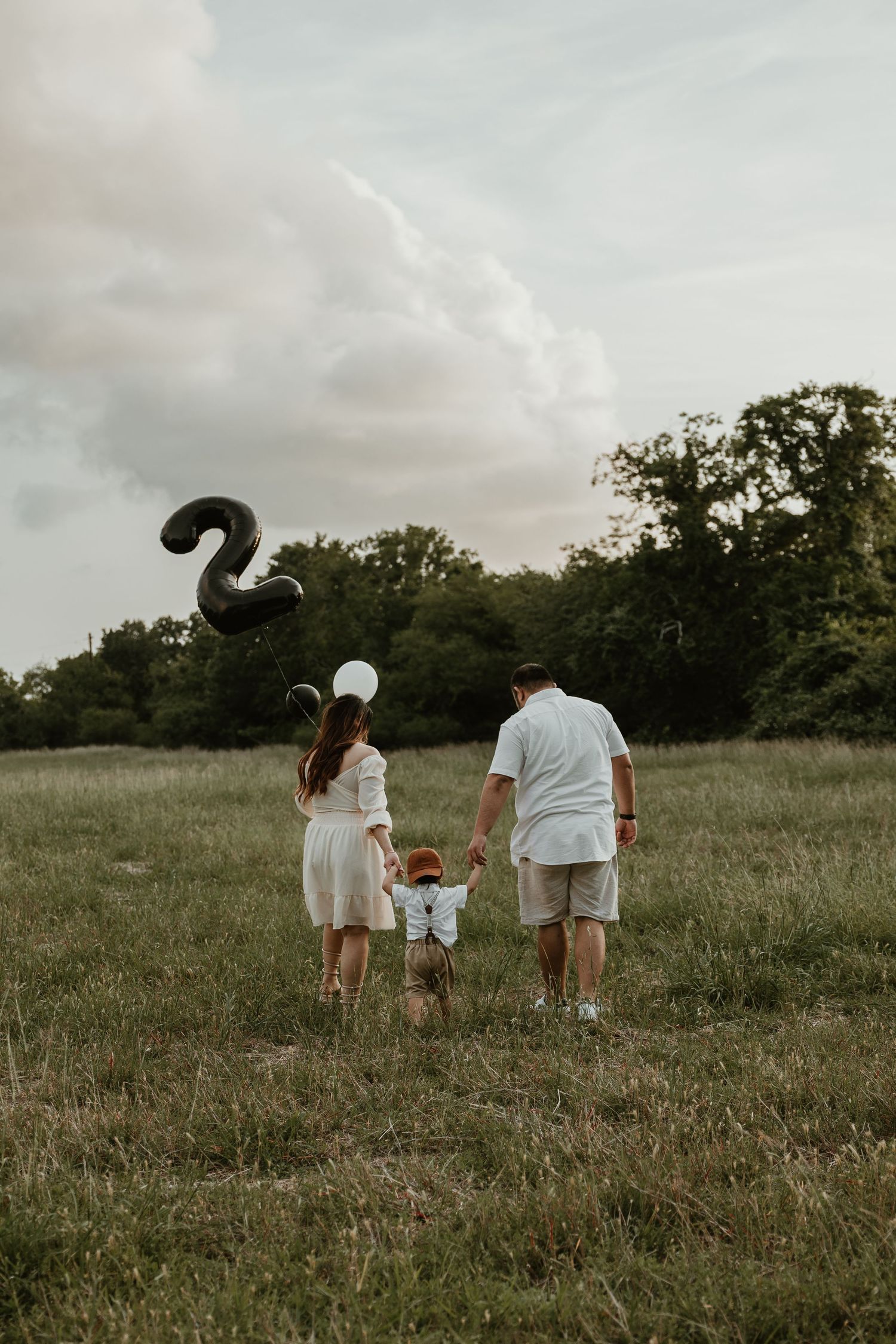 A family walks together through a misty field at dusk wearing white clothing.